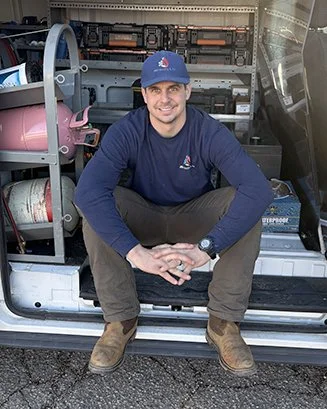 A photo of Ben Haws, owner of JBH Heating & Air Conditioning, sitting in his service van.