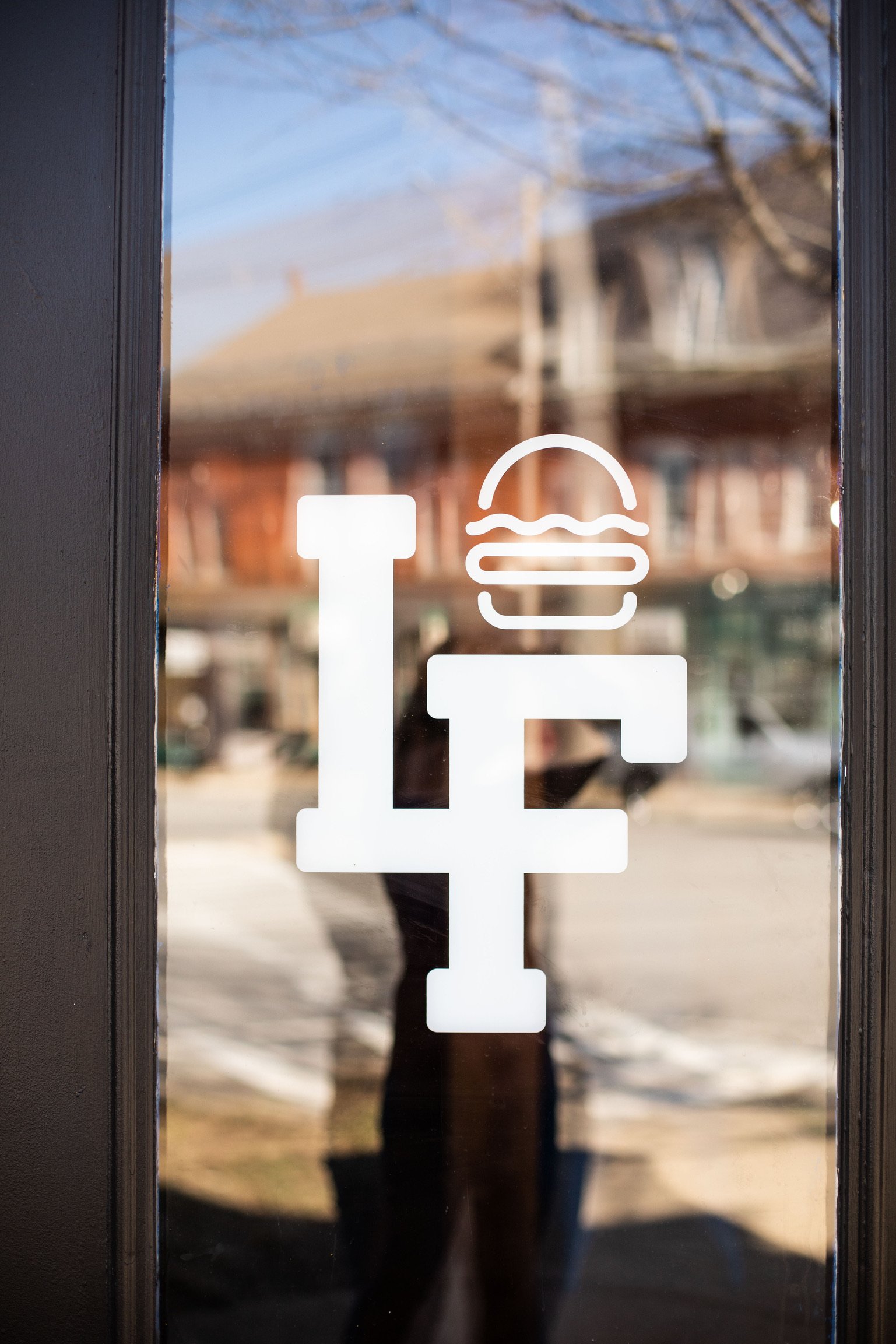 Reflection of a person outside on a glass door with a pizza and drink symbol sticker