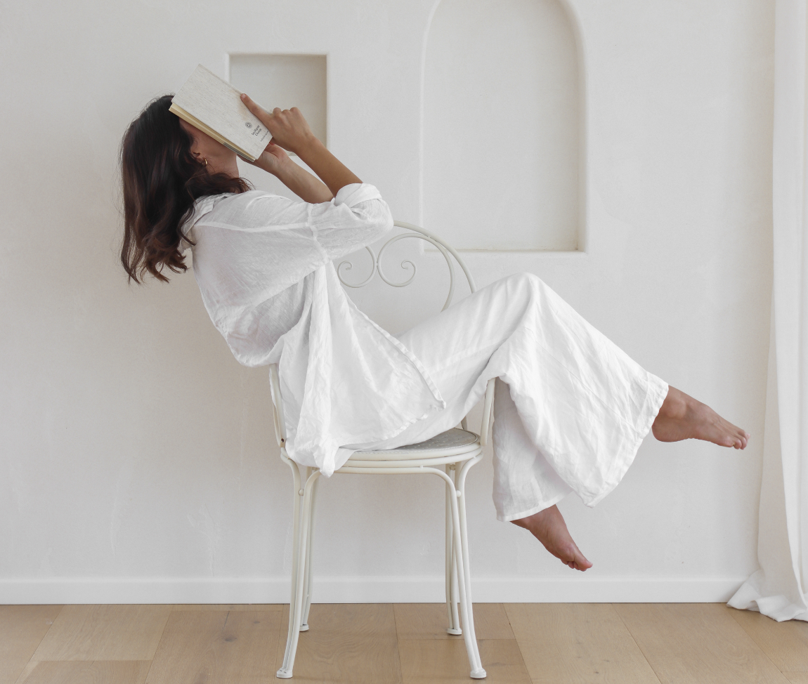 Image of woman sitting in chair with book over her face