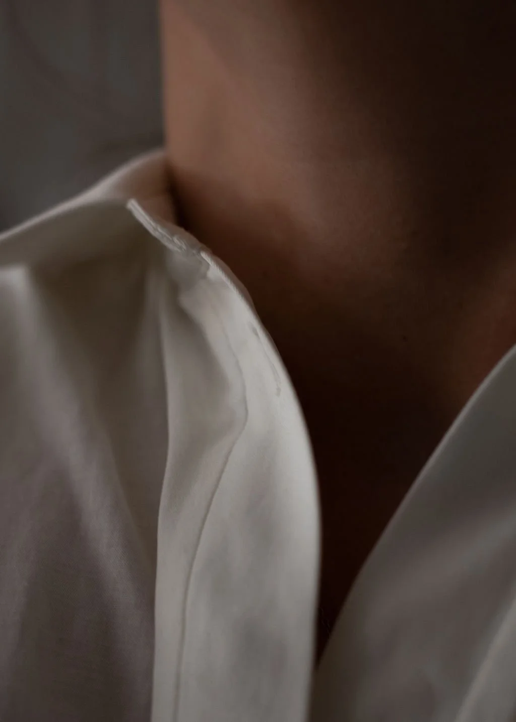 Close-up of a person wearing a white shirt with an open collar, showing part of their neck and shoulder.Katie McFarlan Dakota Design Company Best Client Process Templates for Interior Designers