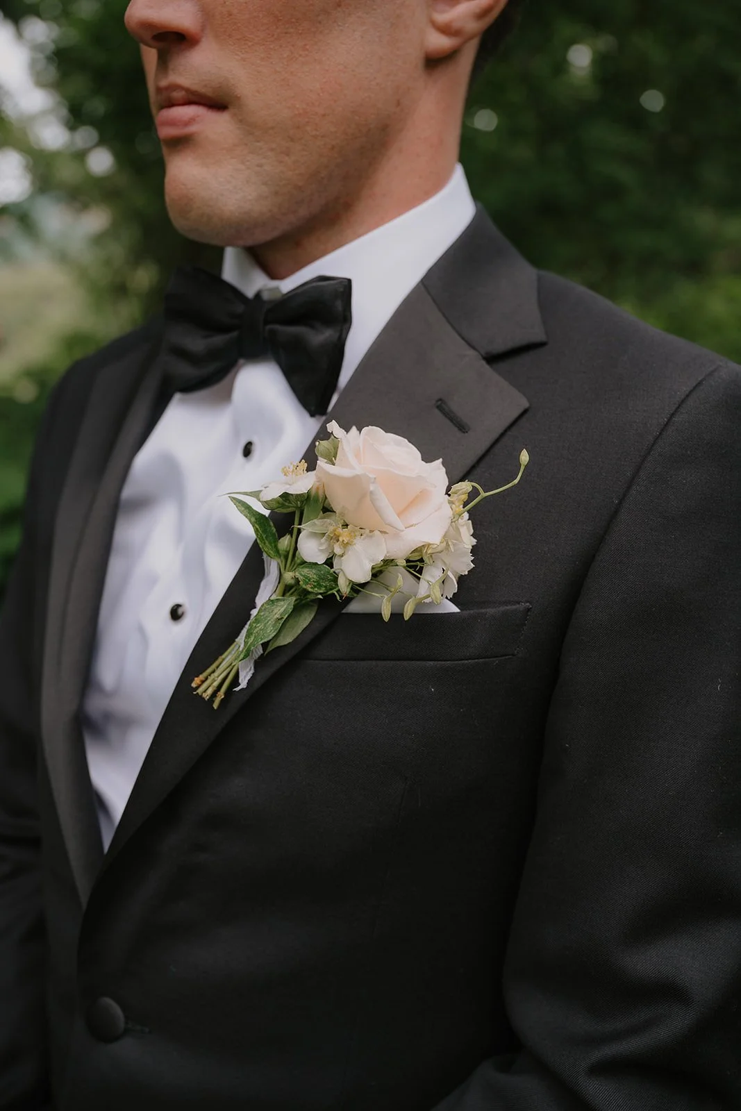 A closeup of the groom's boutonniere. Flowers include a rose paied with mock orange and delphinium.