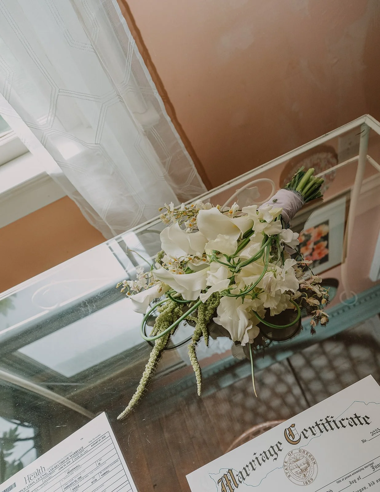 An aerial shot of a modern bridal bouquet of white calla lilies, oncidium orchids, sweet pea, garlic scapes and amaranth.