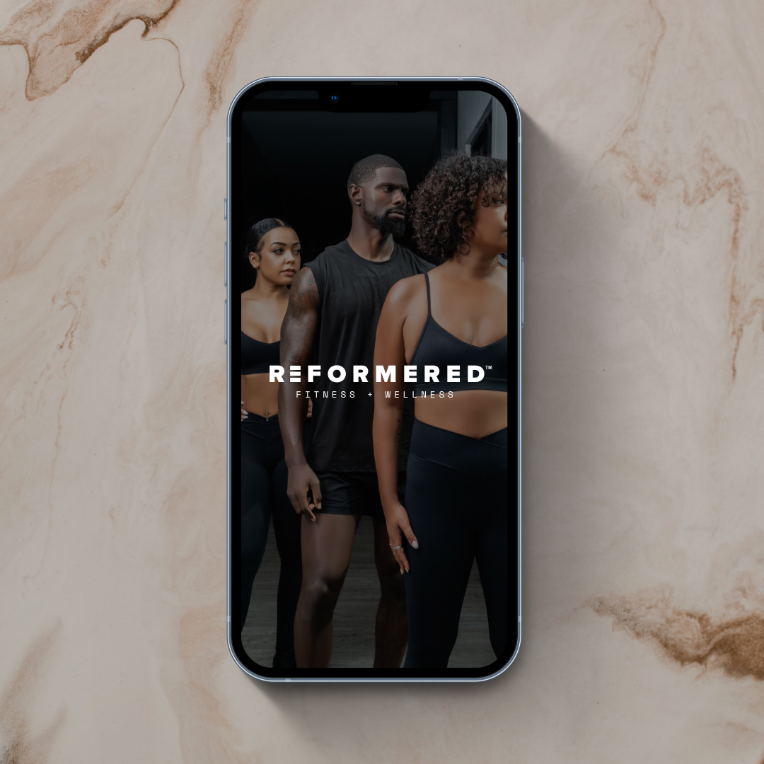 Smartphone displaying an image of three fit people standing in a gym, with the text "Reformered Fitness + Wellness" overlaid.