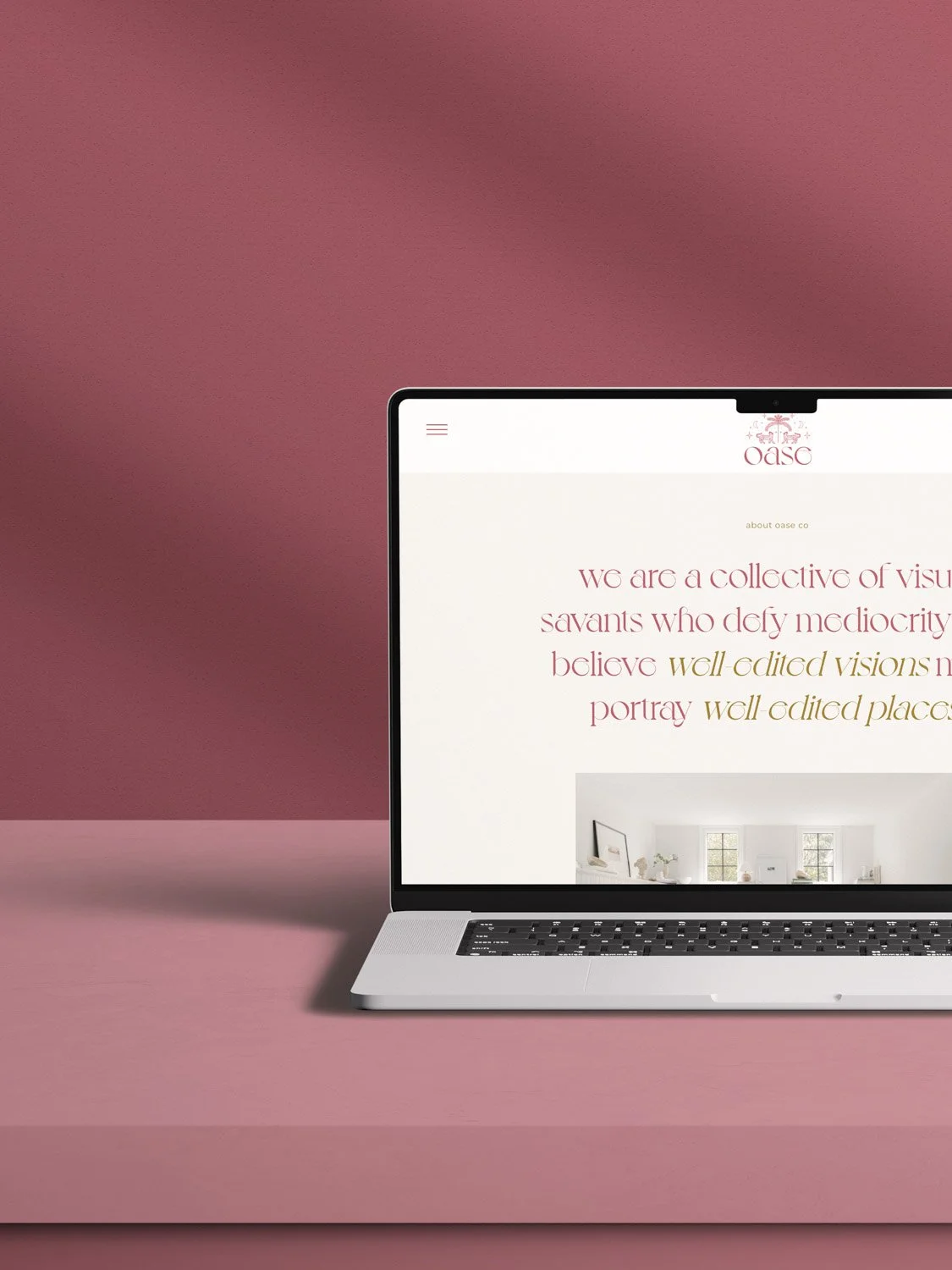 A laptop displaying a website with the text 'We are a collective of visual savants who defy mediocrity, believe well-edited visions, portray well-edited places' against a pink background.