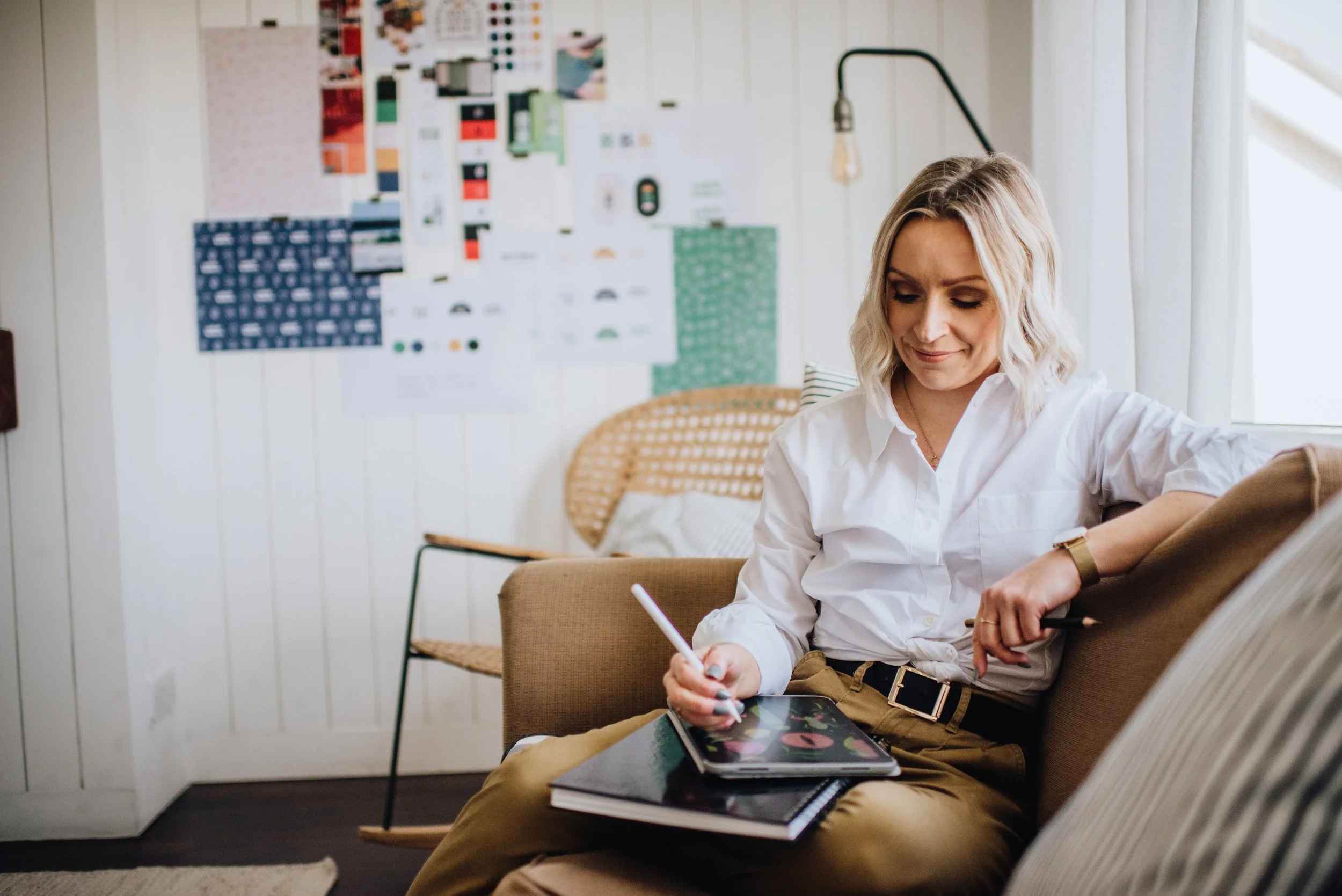 Mari Therese of Studio Marbar sitting on a couch working on illustrations