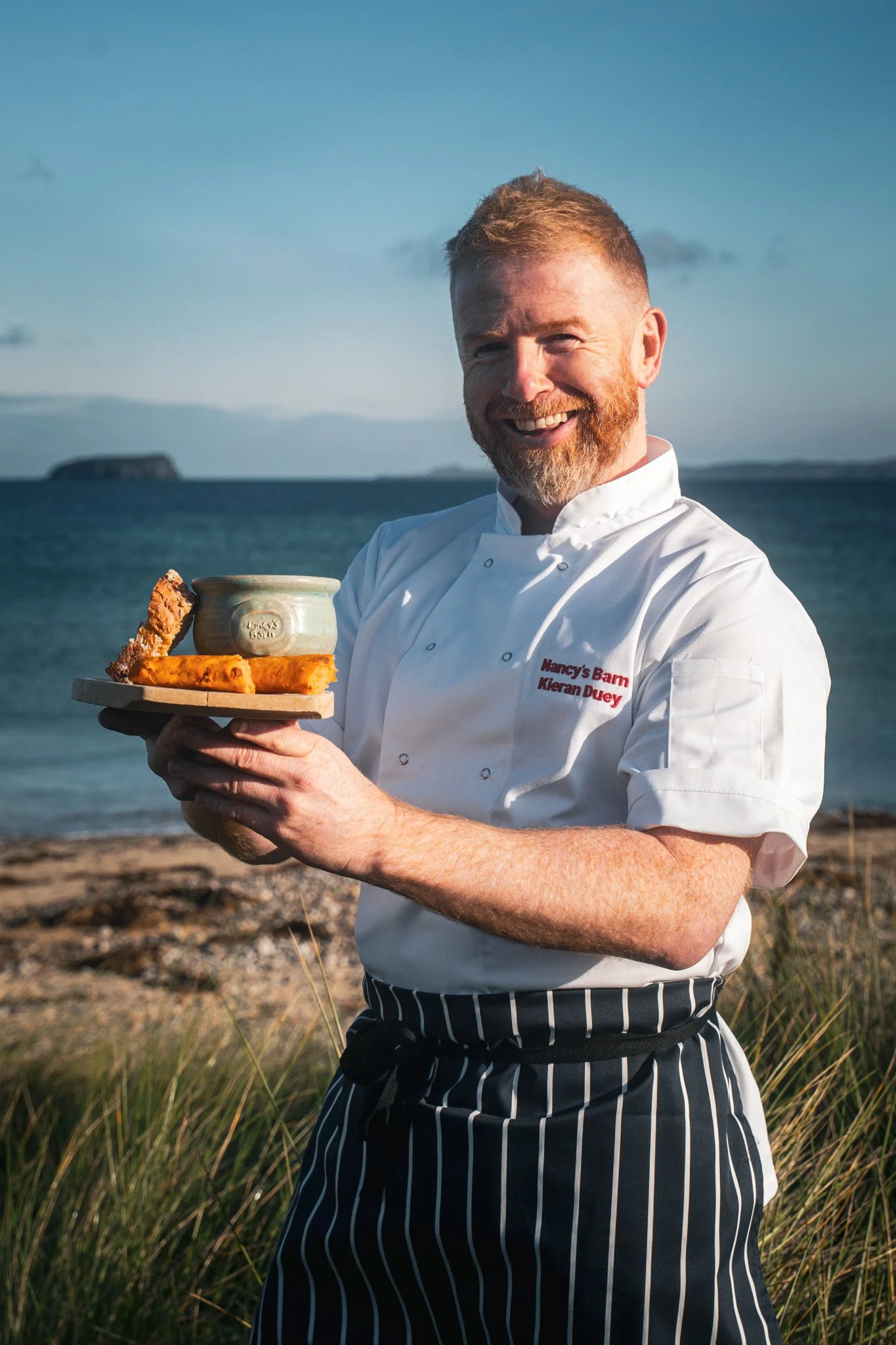 Kieran Doherty holds a pot of his world award winning seafood chowder in front of Glashedy Island, Pollan Strand, Co Donegal