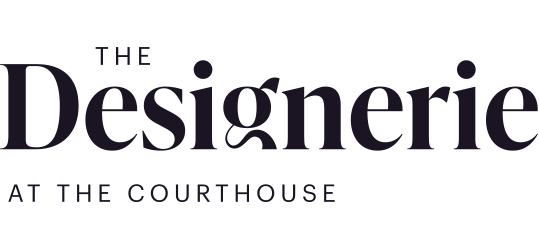 Logo for The Designerie at the Courthouse in a minimalist style with light blue text on a black background.
