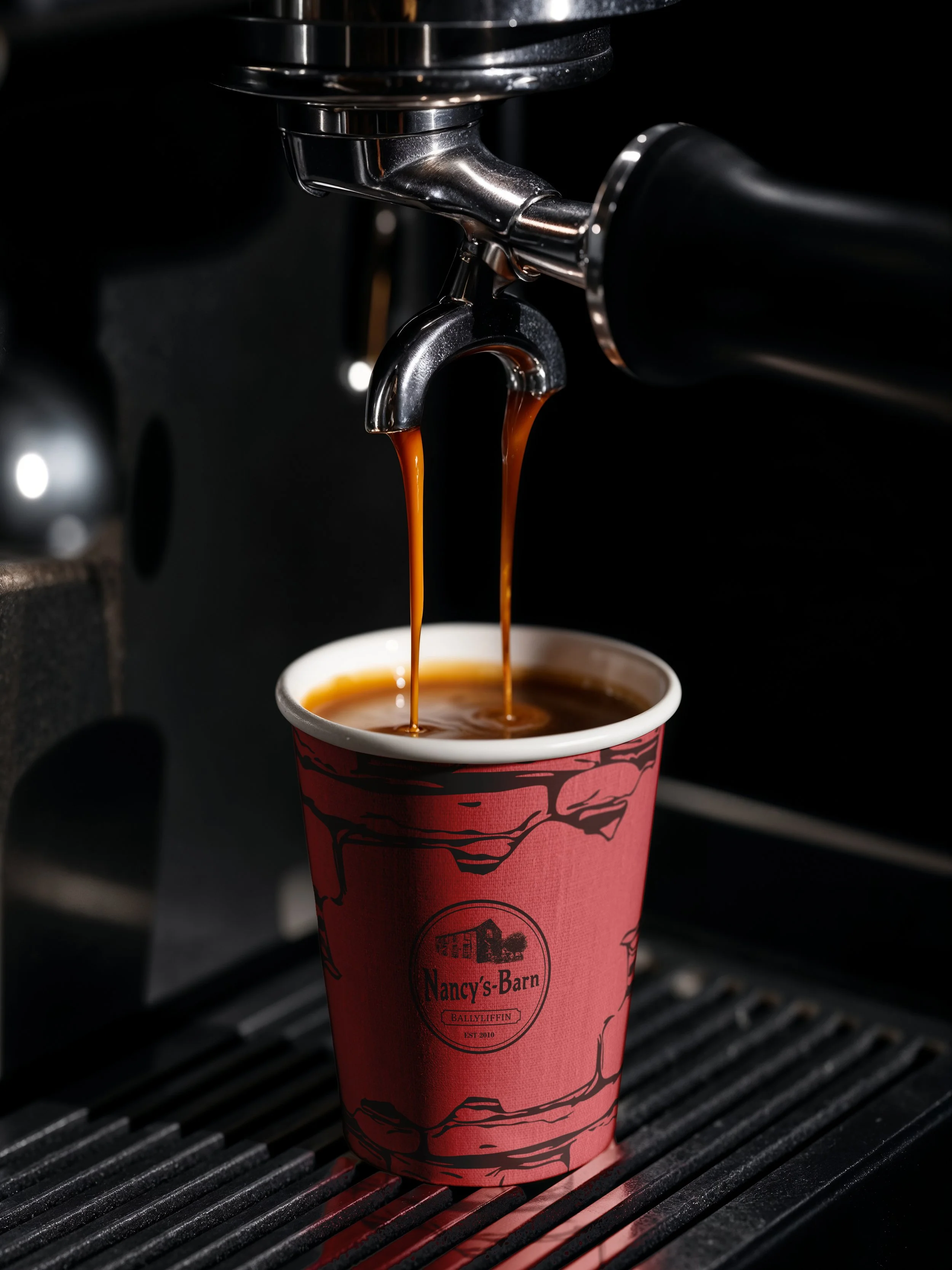 a Nancy's Barn coffee cup under a barista machine