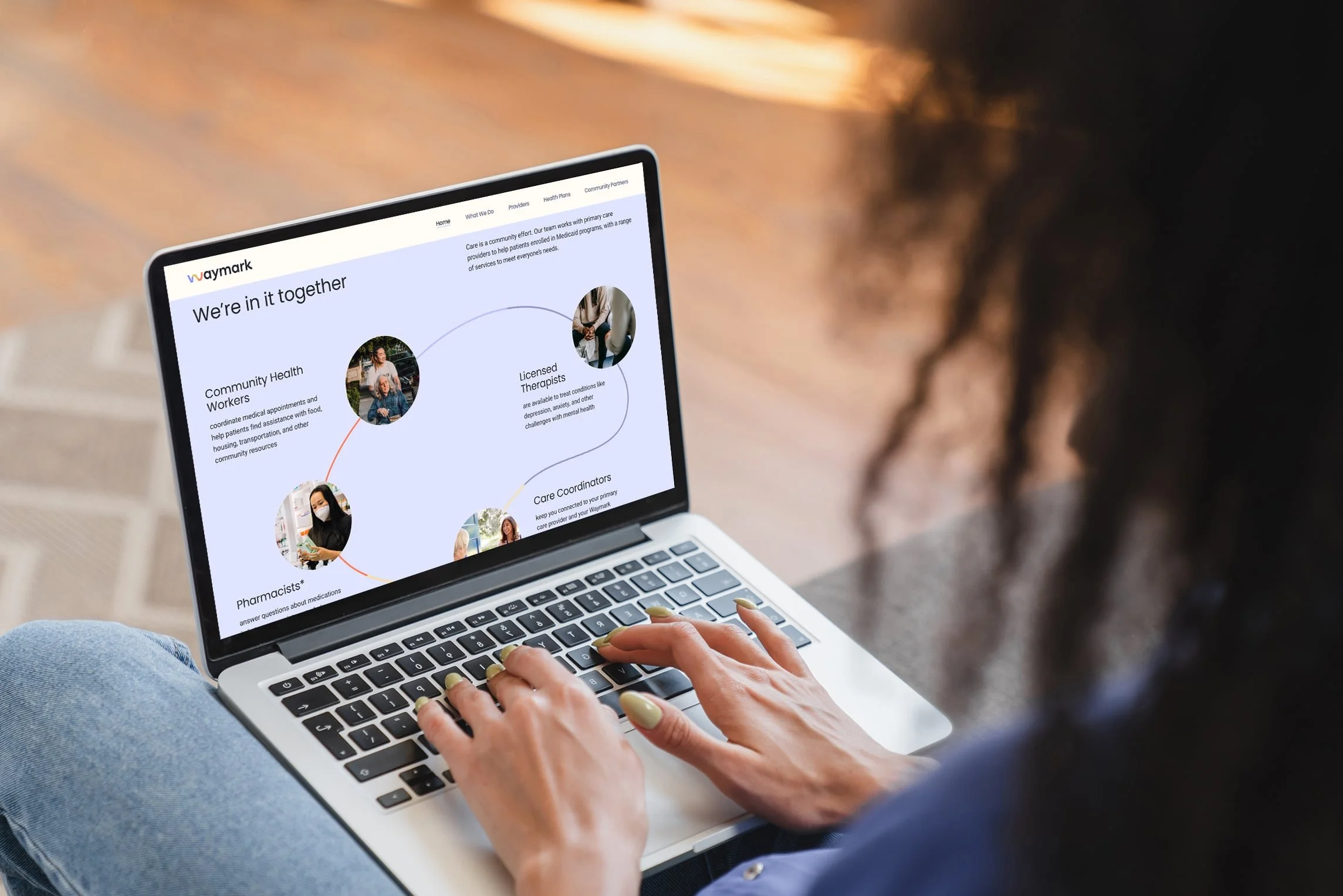 Person using a laptop, viewing a webpage about healthcare team members including community health workers, licensed therapists, pharmacists, and care coordinators.