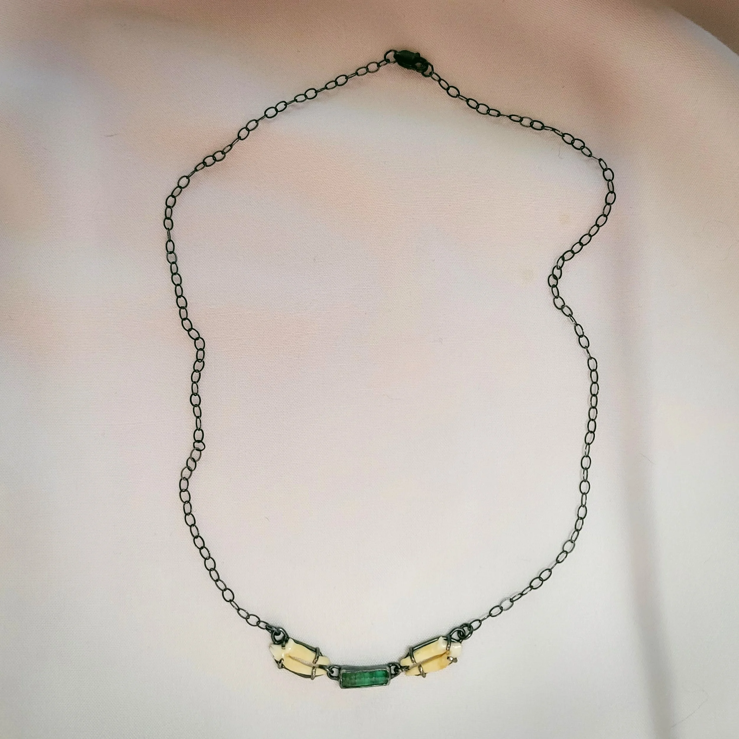 Raw emerald, small animal teeth, and sterling silver. $600.