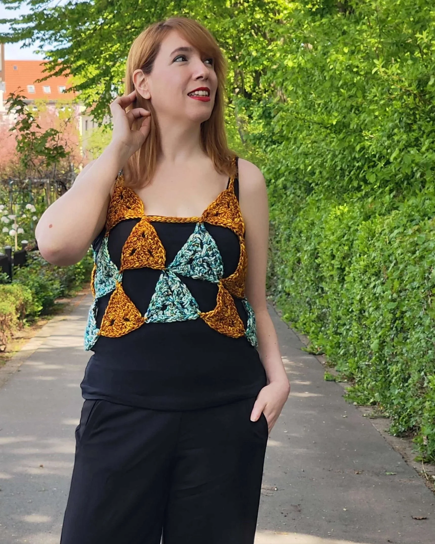 Person wearing a black outfit, and over it, a crochet triangle shirt made with Malabrigo Noventa yarn