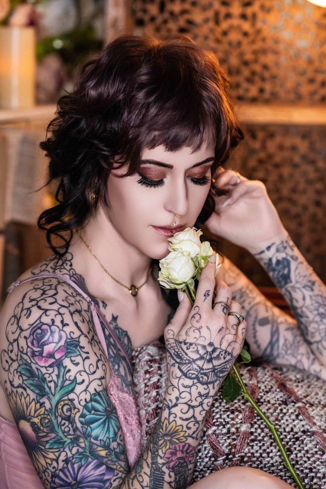 Tattooed woman holding white roses during a boudoir session at our Timnath studio near Fort Collins