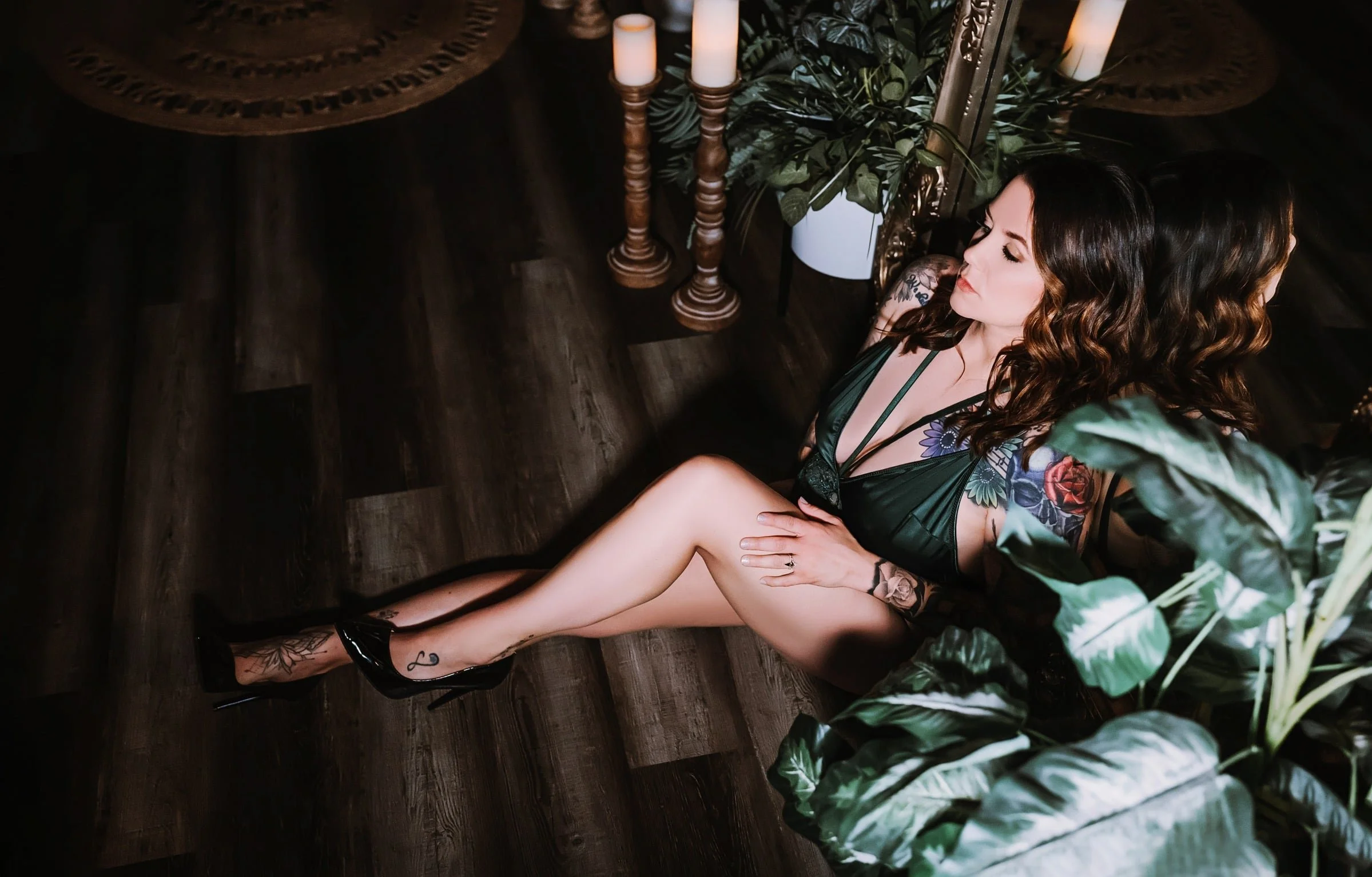 Woman in green lingerie surrounded by candles and plants in our private boudoir studio
