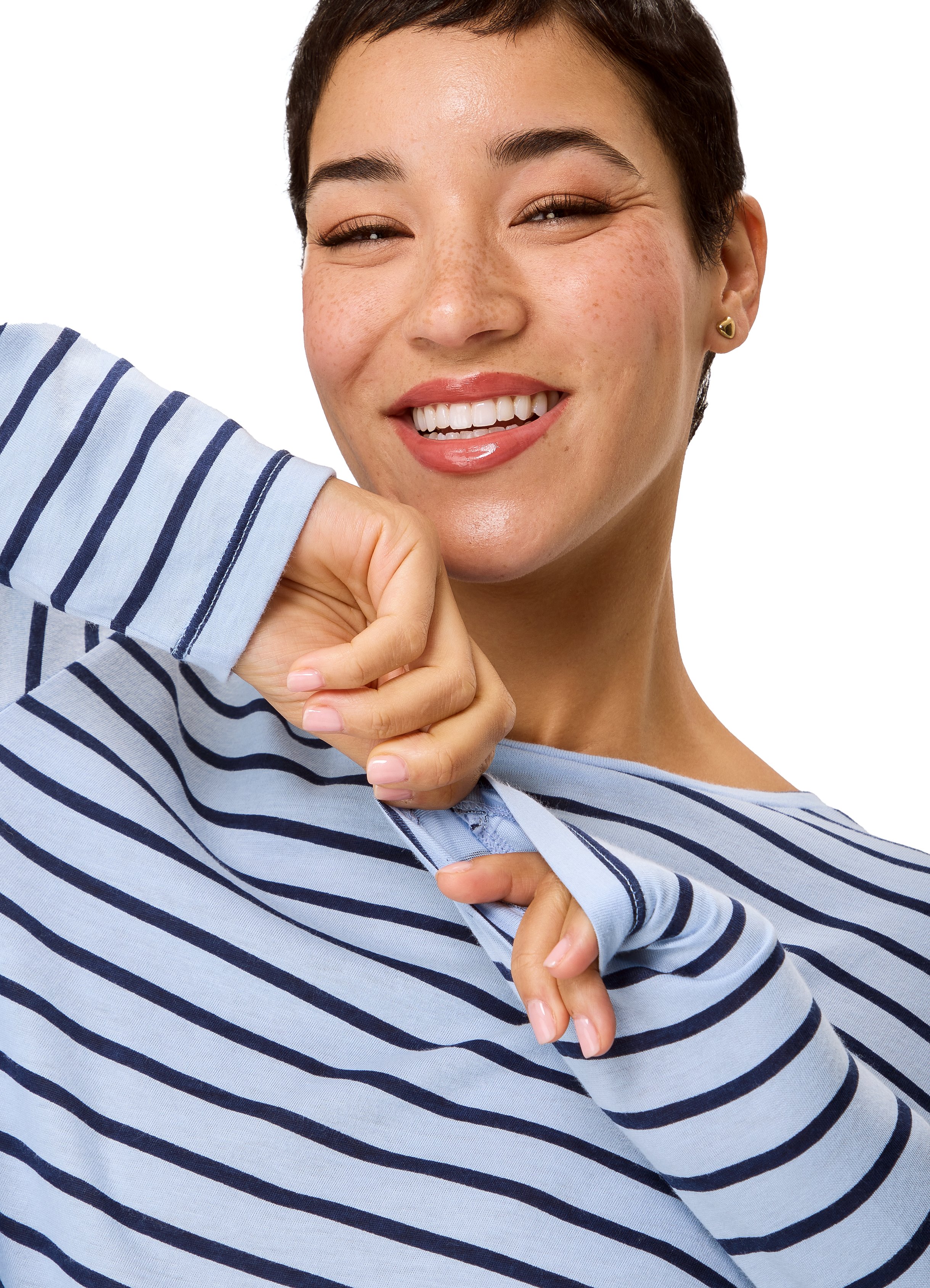 Close-up of a smiling woman with short dark hair, freckles, wearing a blue and white striped shirt, holding the collar with her right hand, against a white background.