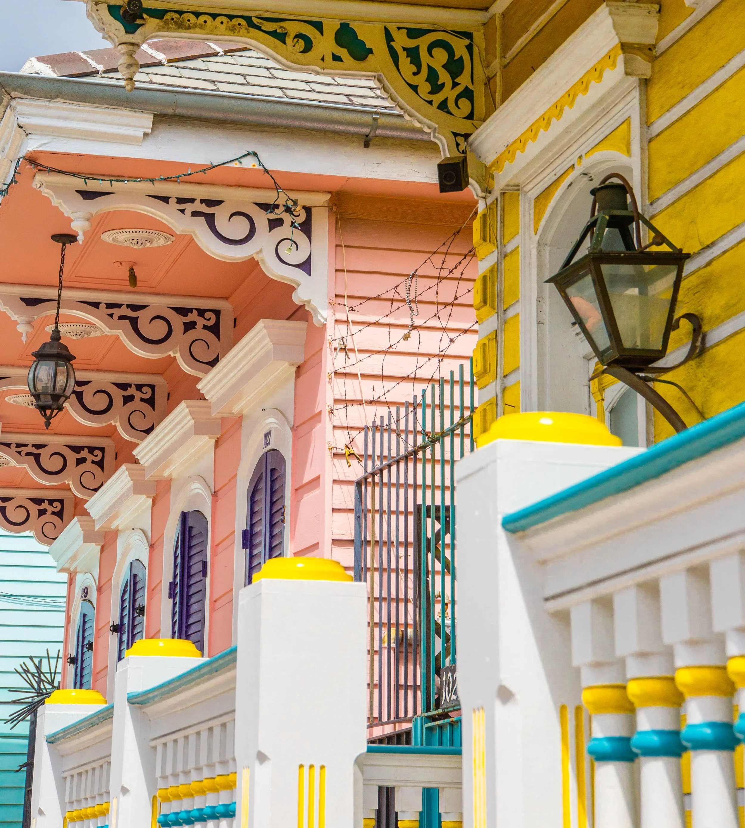 Colorful houses with decorative trim, yellow and pink walls, black lanterns, and string lights decorate the porch area.