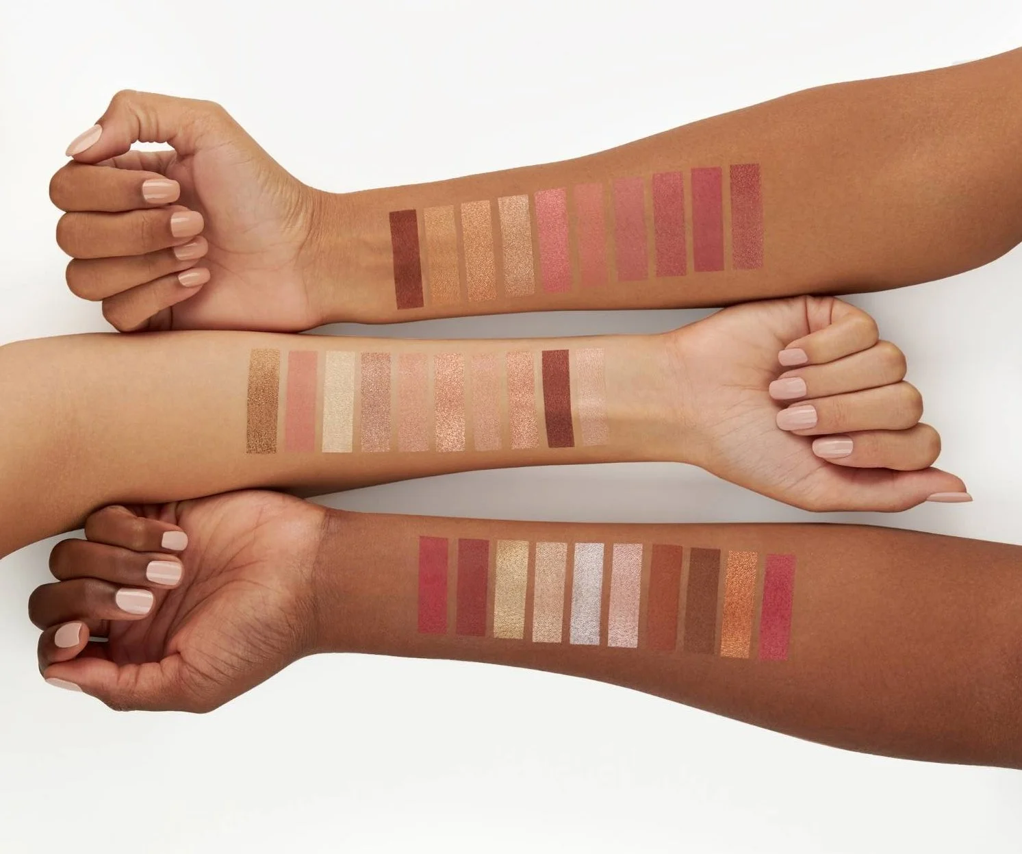 Three arms with various skin tones displaying swatches of different lipstick shades.