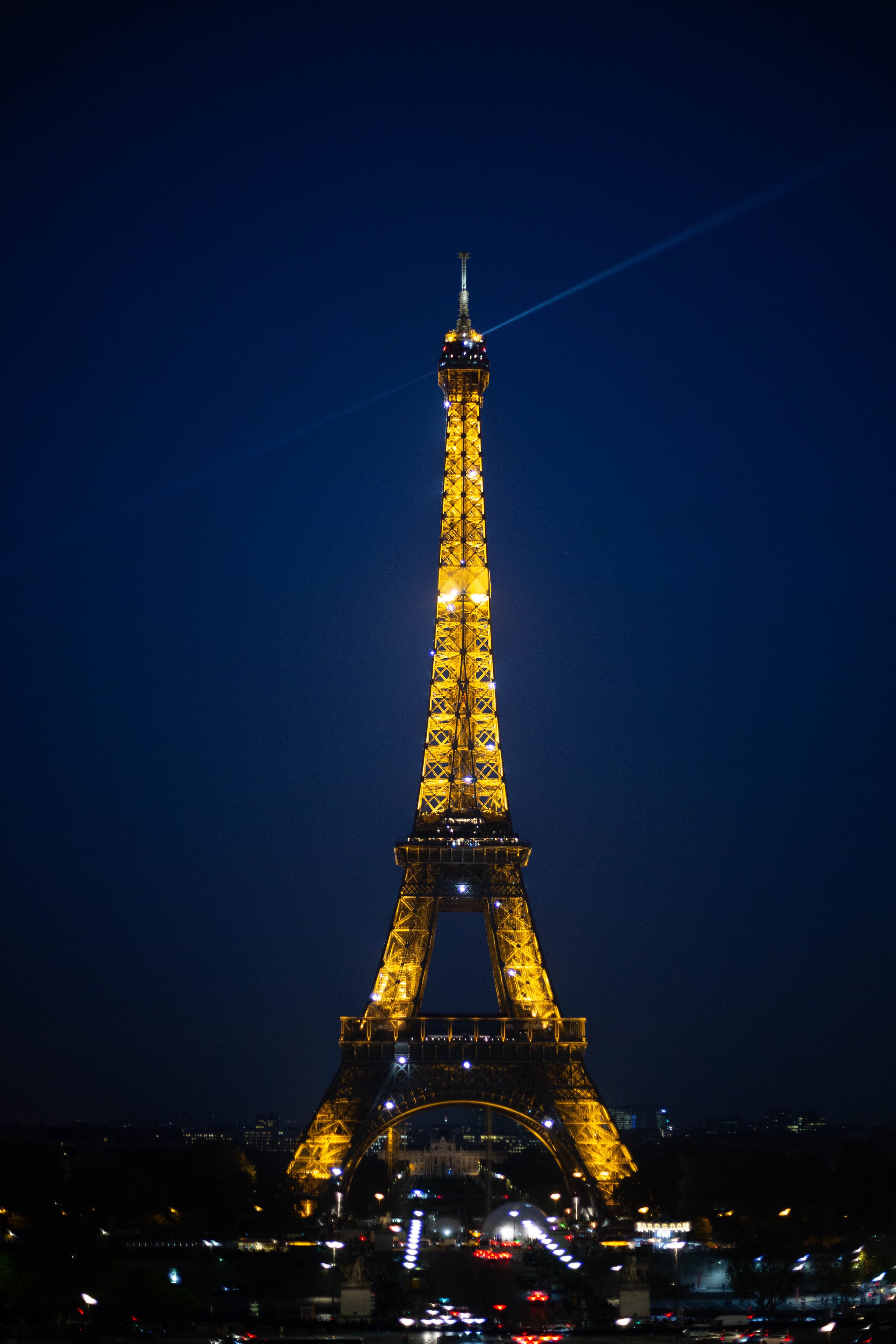 The Eiffel Tower illuminated at night with a clear, dark sky in the background and city lights at the base.