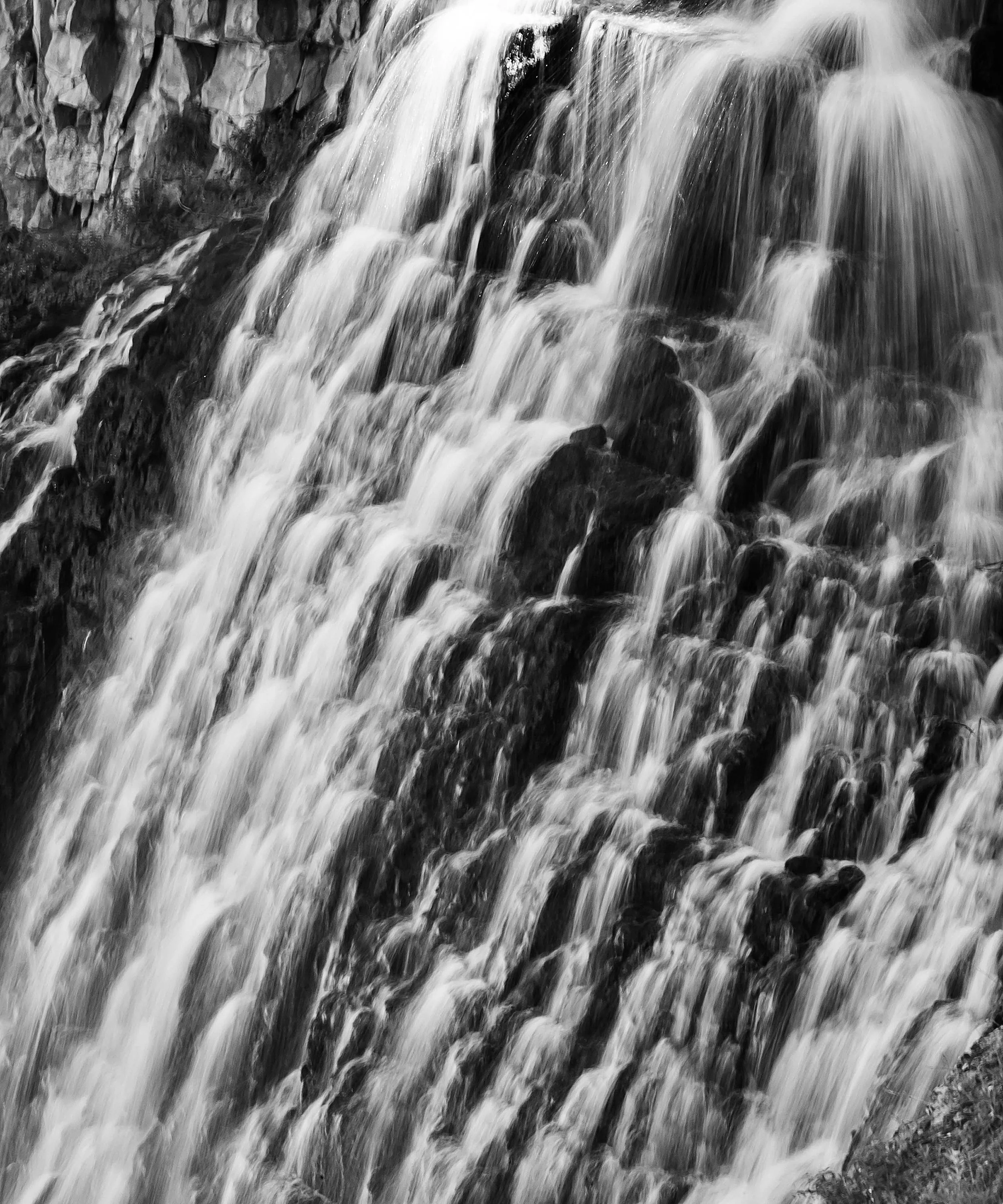 Black and white photo of a waterfall flowing over rocks.