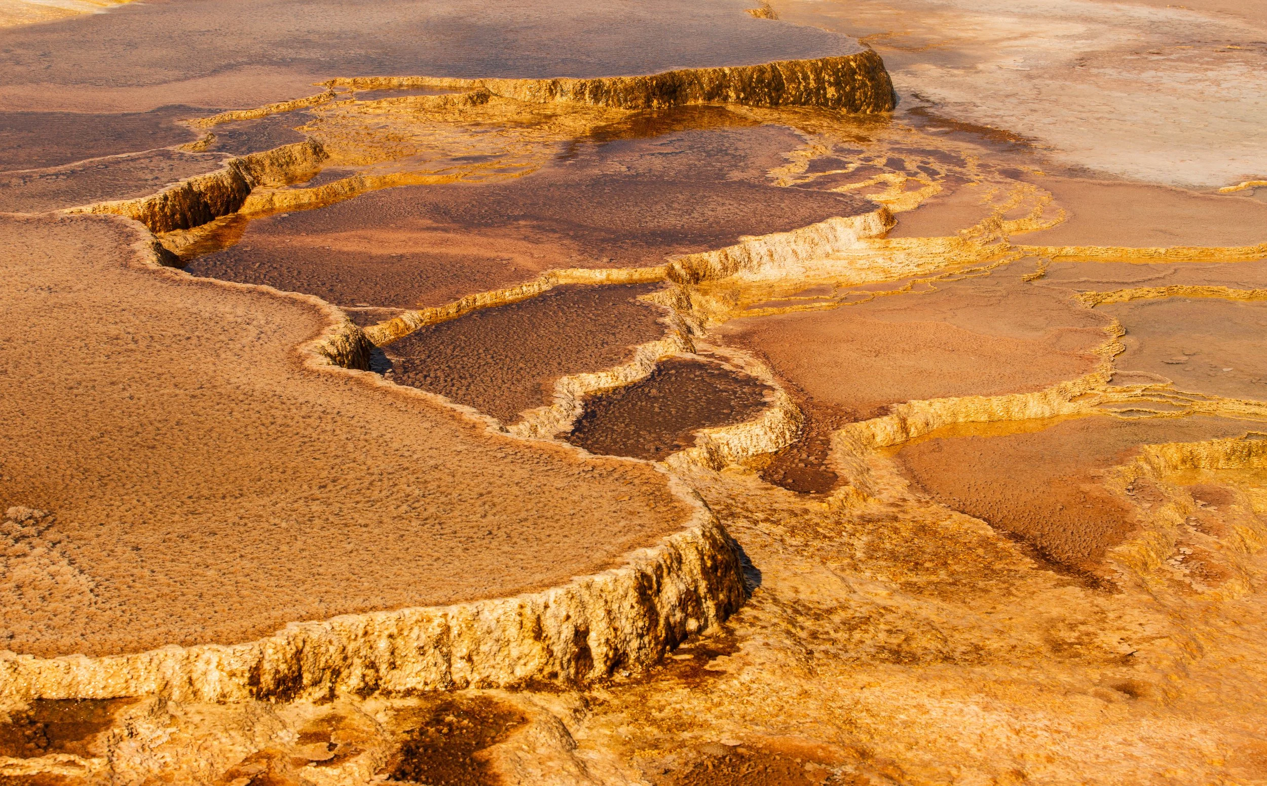 Close-up view of colorful, layered mineral deposits forming terraces in a geothermal area.