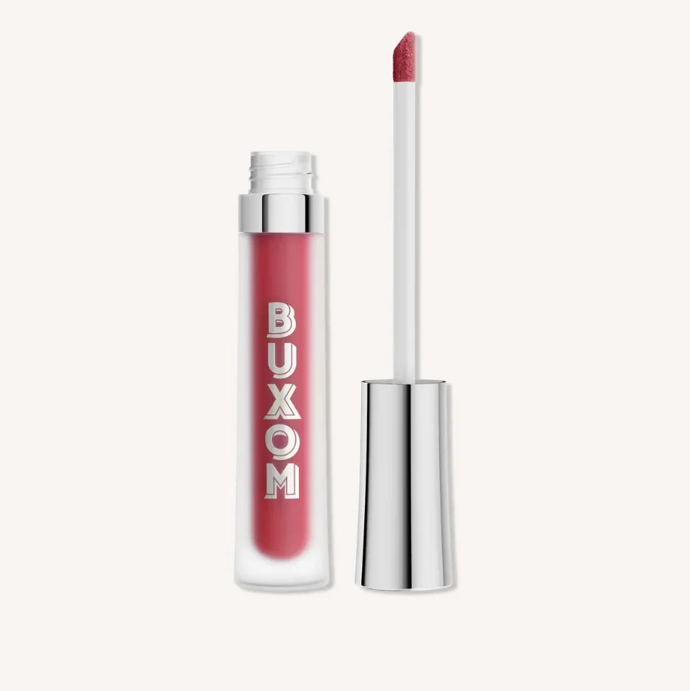 A tube of pink liquid lipstick with a silver cap, with the lid off showing a doe-foot applicator, on a white background.