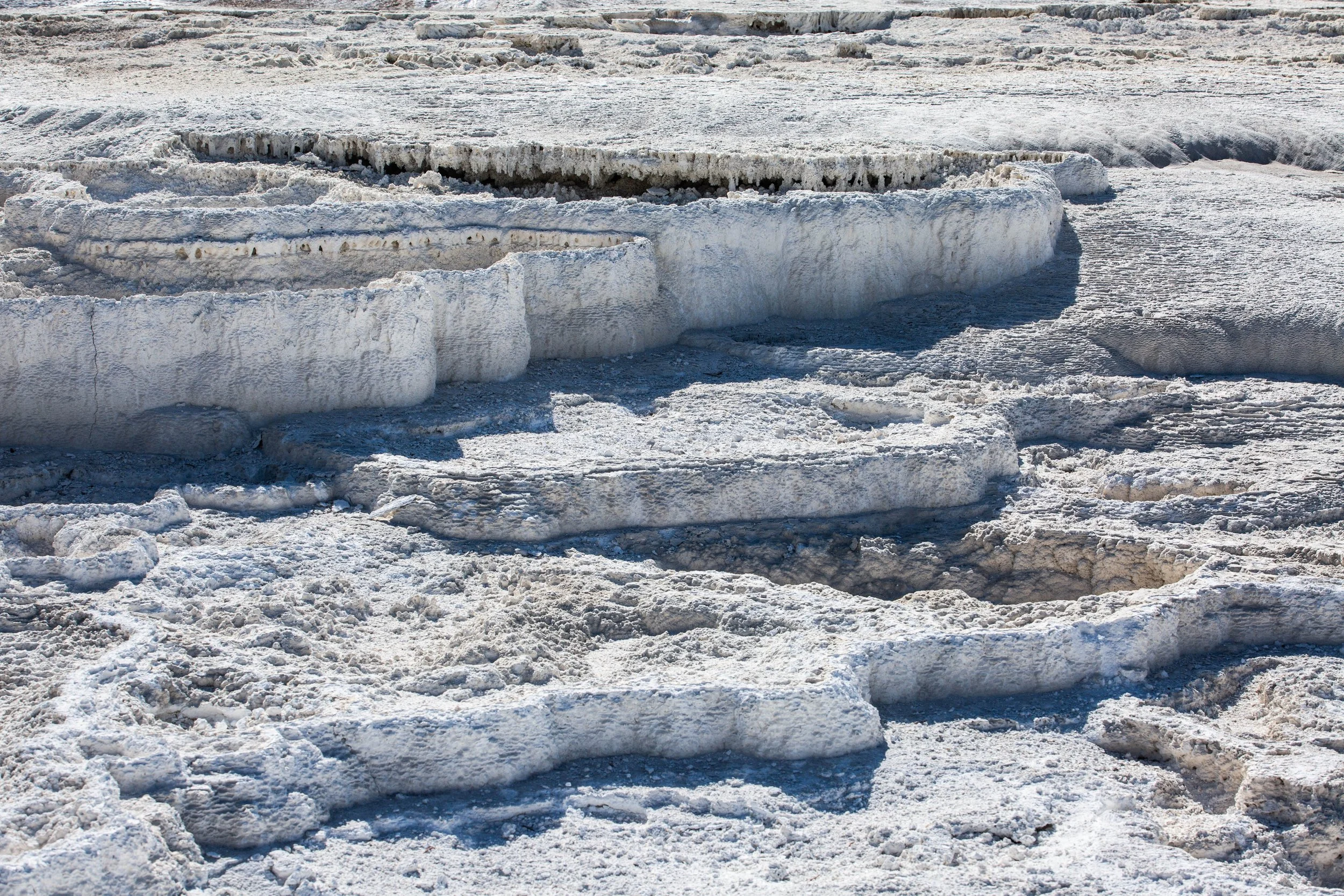 Close-up of snow and ice formations on a cold ground, with various layers and textures of snow and ice.