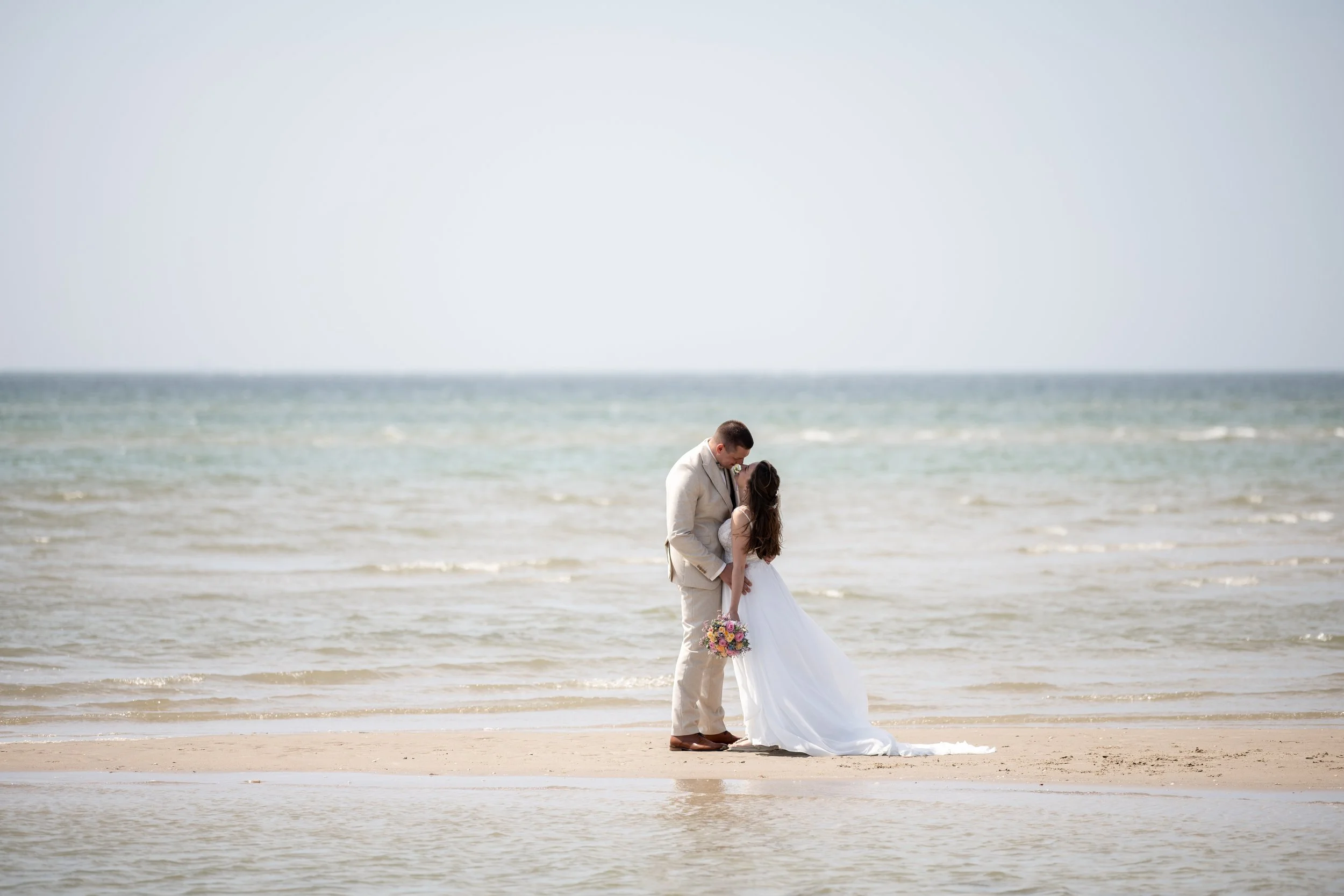 An intimate wedding couple hugging on the wild and windy beach of the Danish West Coast during their North Sea elopement
