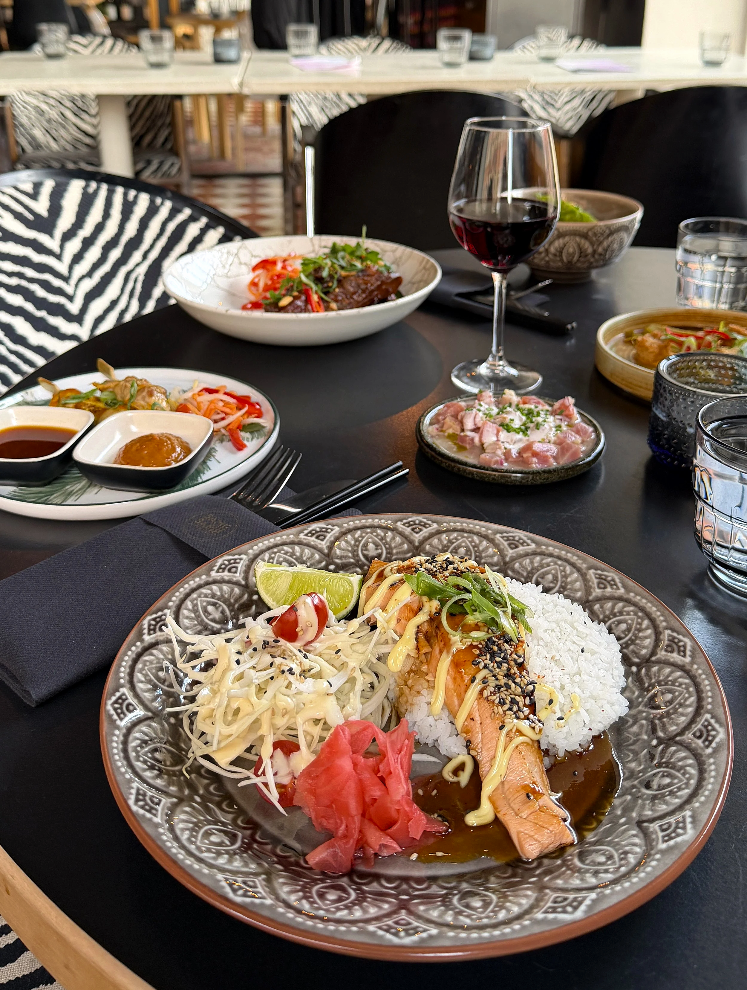 Värikäs annos. Lautasella riisiä, teriyaki lohta, kevätsipulia, sekä pikkeleitä, inkivääriä ja limelohko.