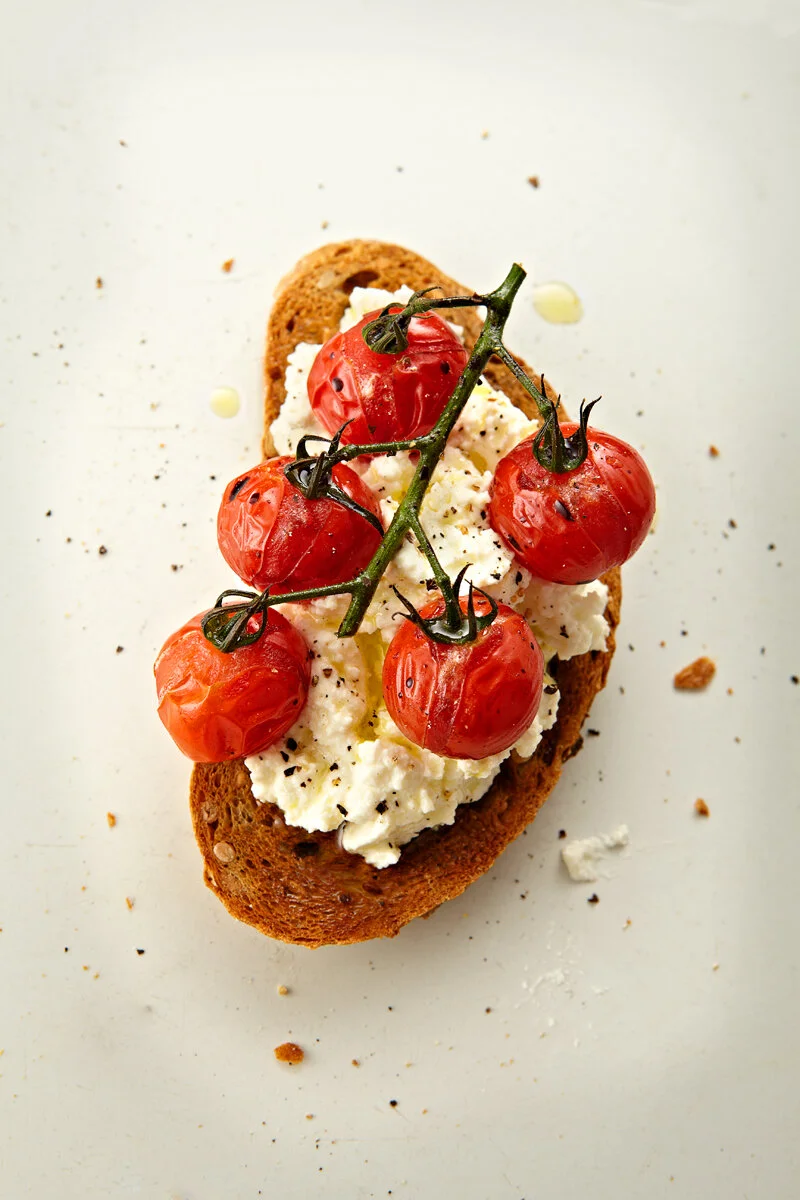 Cherry tomatoes on ricotta on toast as a bruschetta shot by food and drink photographer and director based in London Scott Grummett.