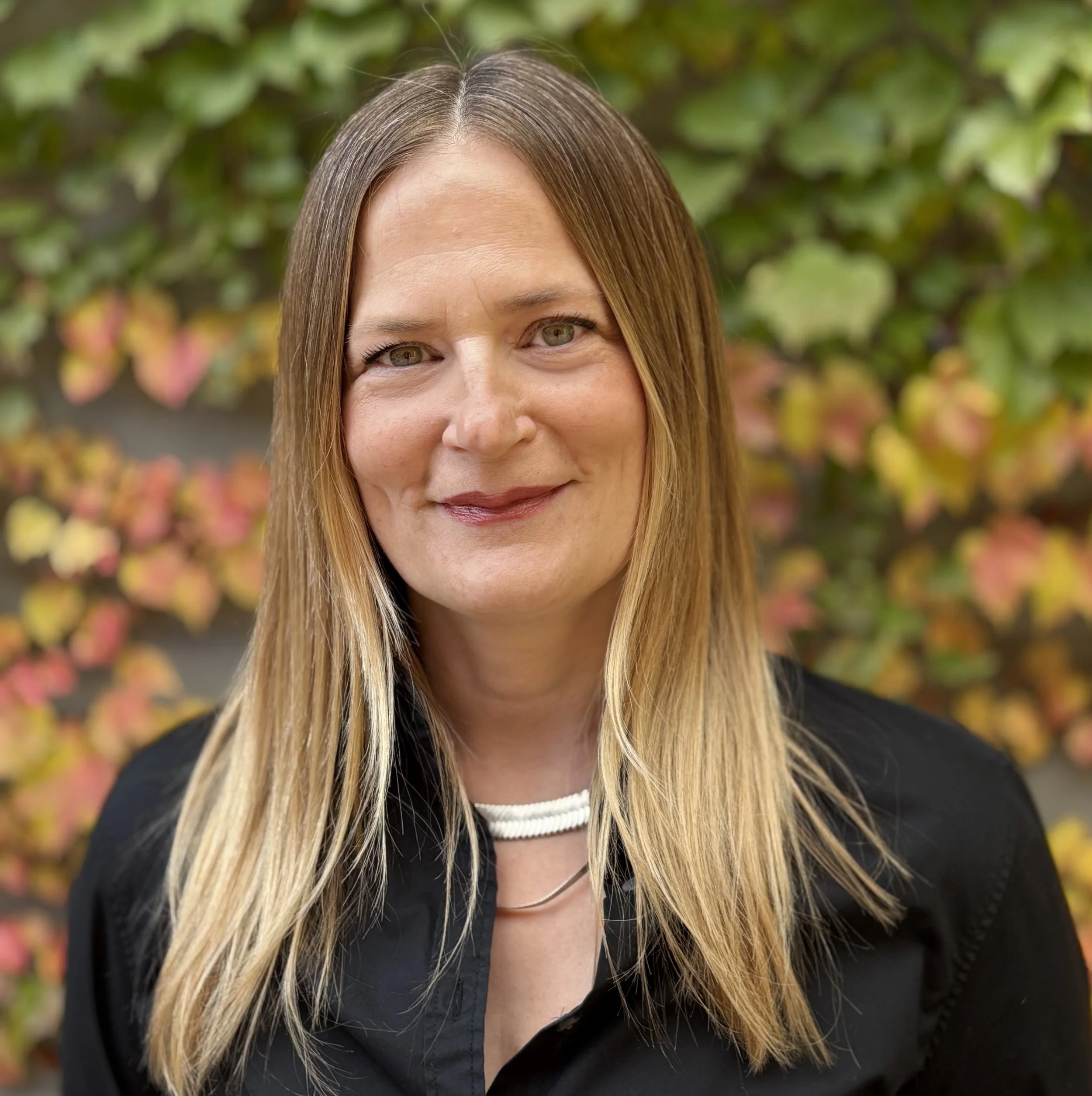 Andrea, affordable art therapist, poses in front of foliage
