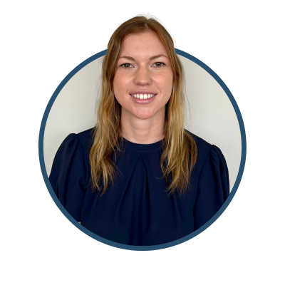 Person smiling with long hair, wearing a dark blouse, framed in a circular border, against a plain background.