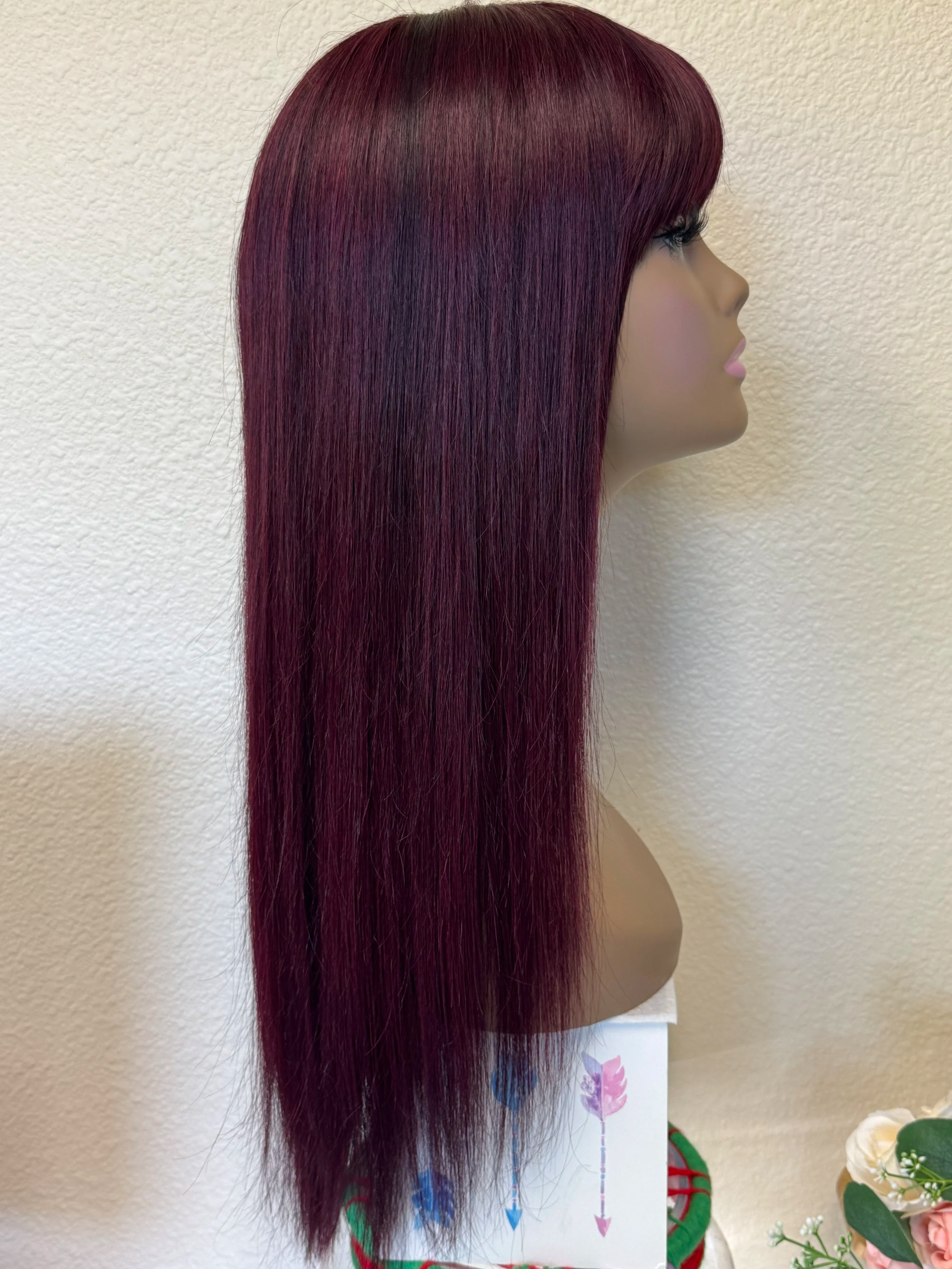 Black+Wine+straight+Remy+human+hair+wig+with+full+bangs%2C+deep+burgundy+color%2C+and+naturally+thin+tapered+ends+displayed+on+a+mannequin.side+.png
