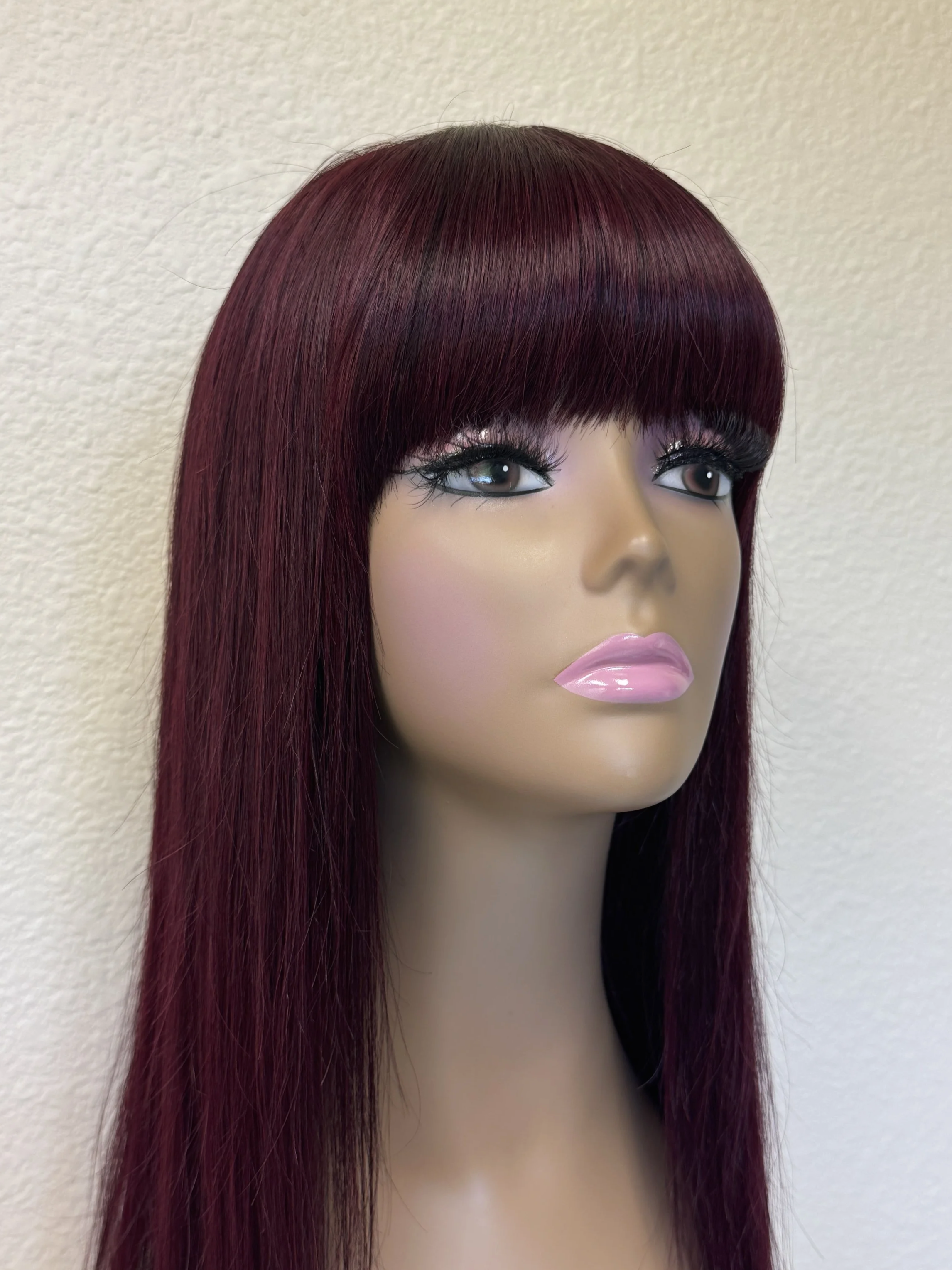 Black+Wine+straight+Remy+human+hair+wig+with+full+bangs%2C+deep+burgundy+color%2C+and+naturally+thin+tapered+ends+displayed+on+a+mannequin.close+up.png