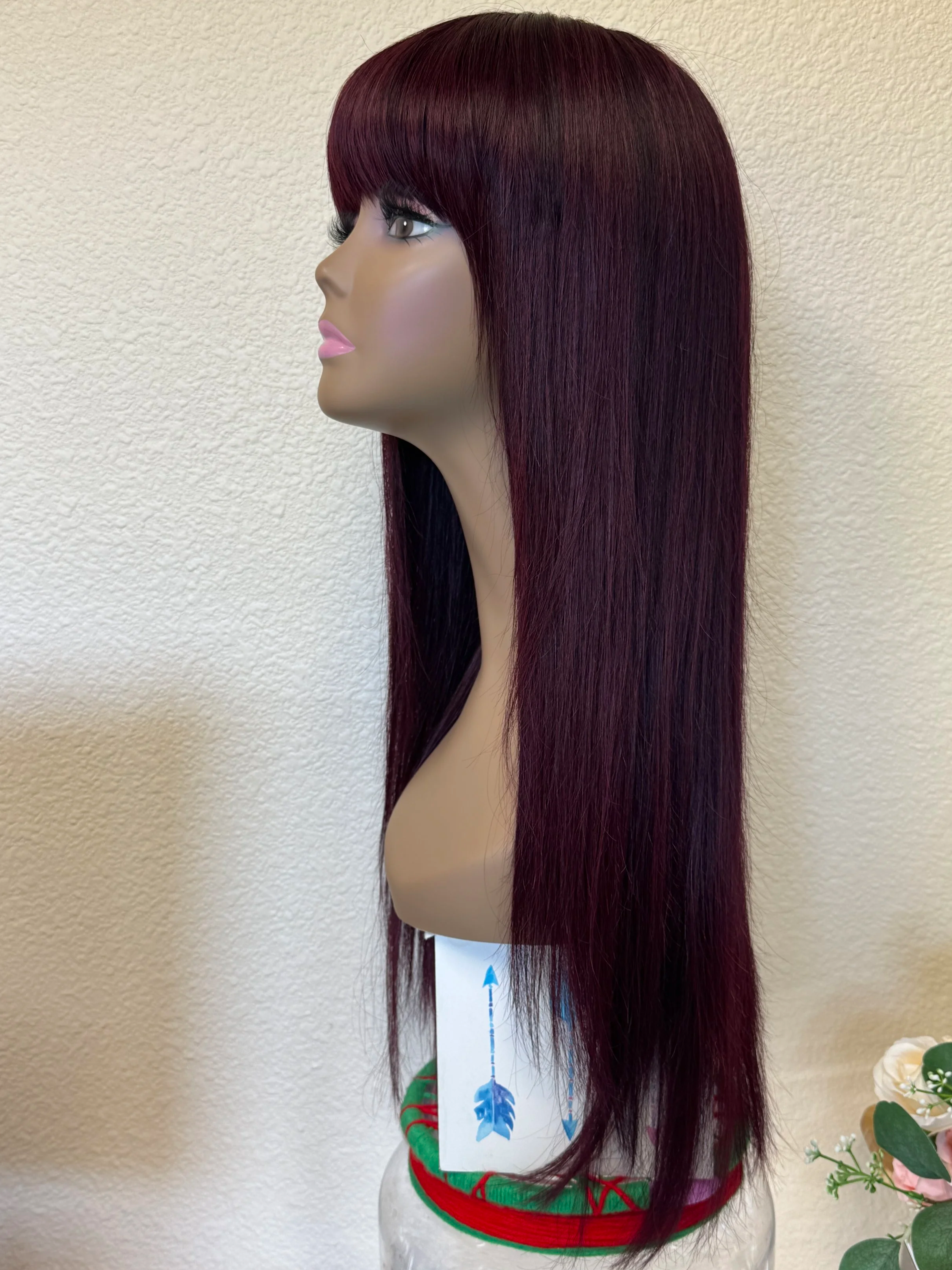 Black+Wine+straight+Remy+human+hair+wig+with+full+bangs%2C+deep+burgundy+color%2C+and+naturally+thin+tapered+ends+displayed+on+a+mannequin+side+view.png