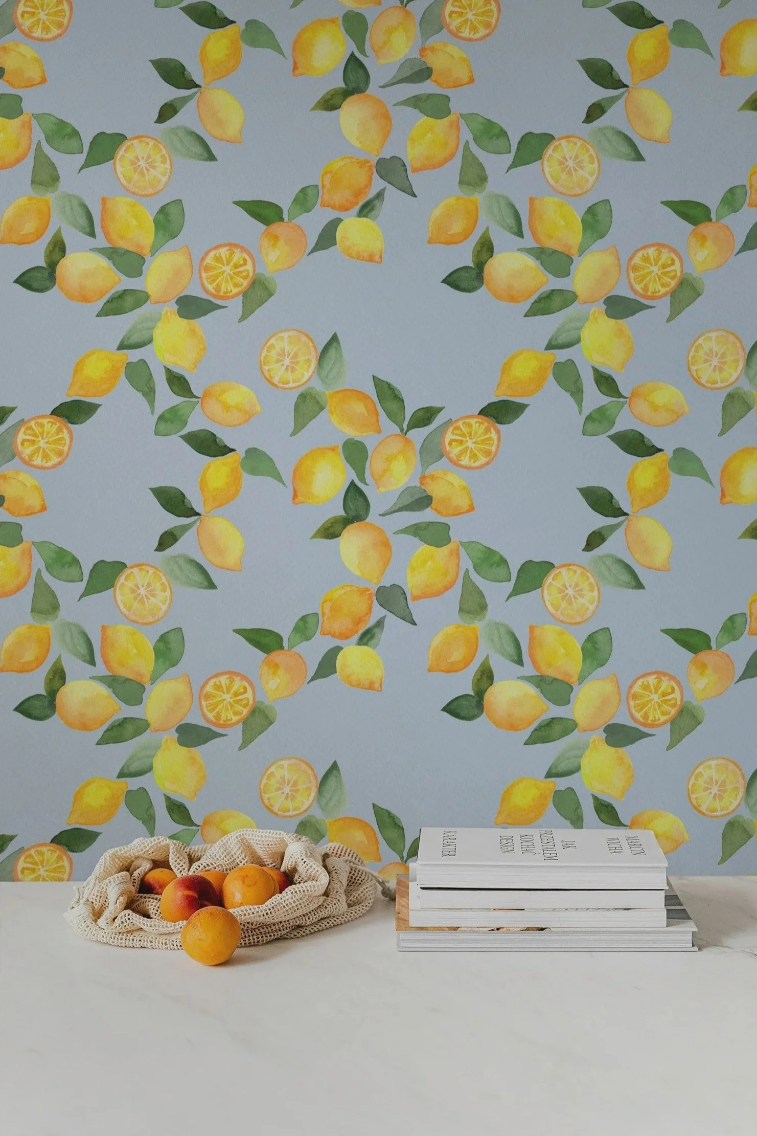 A table displays a basket of peaches and apricots, with a backdrop of lemon-patterned wallpaper.