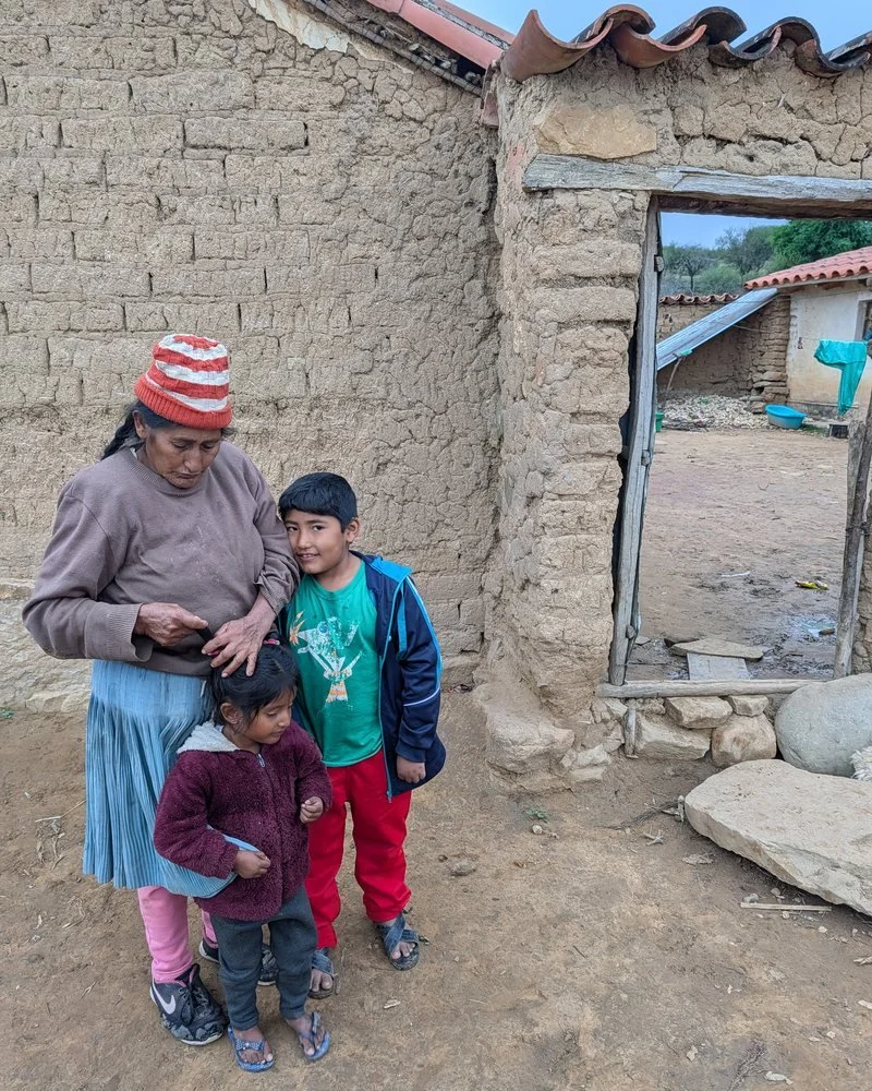 A mother and two children outside their home in San Julián Bajo