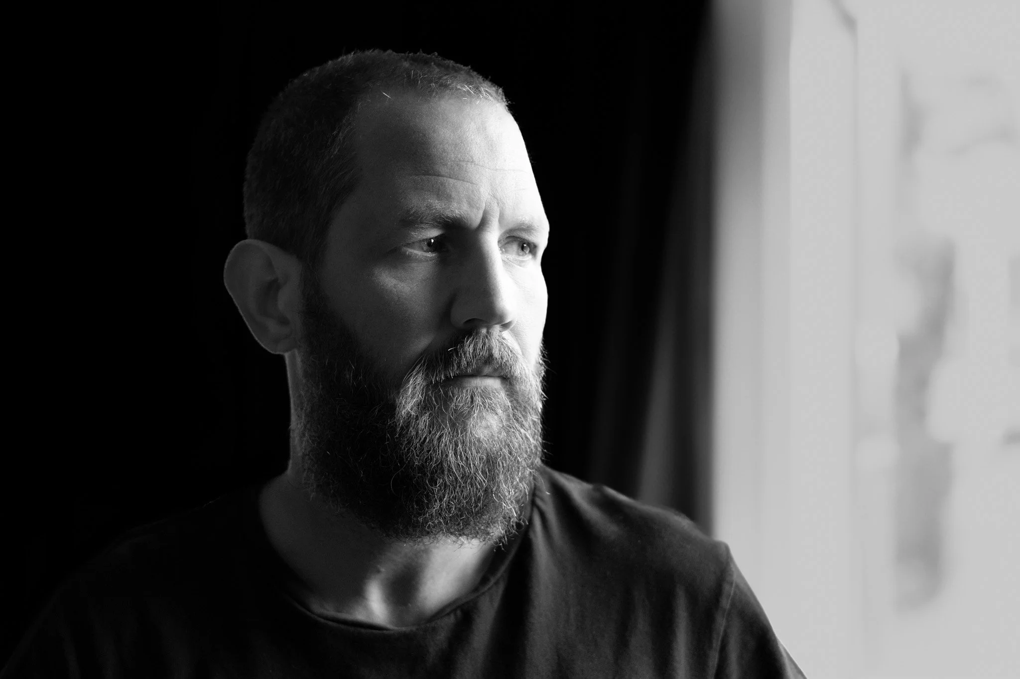 A black and white photograph of the artist, Renzo Brandsma,  looking out of a window.