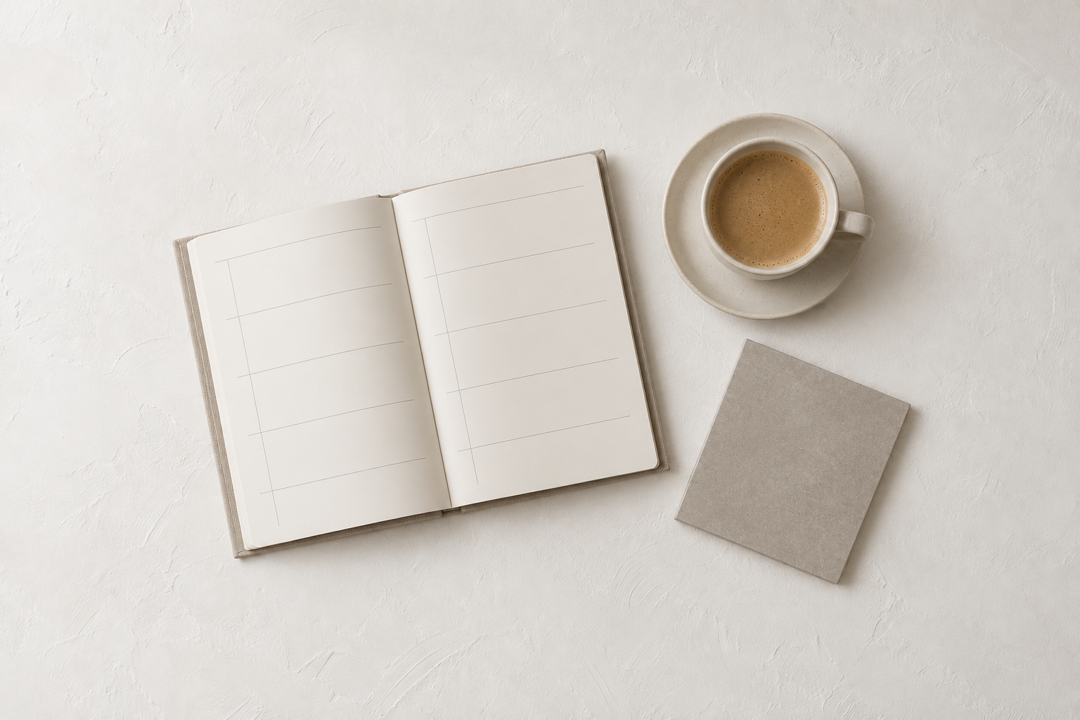 Open paper planner, ceramic coffee cup, and a gray tile sample on a white plaster surface.
