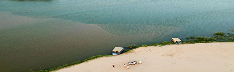 Aerial view of a secluded sandbar with two sun umbrellas at the water's edge