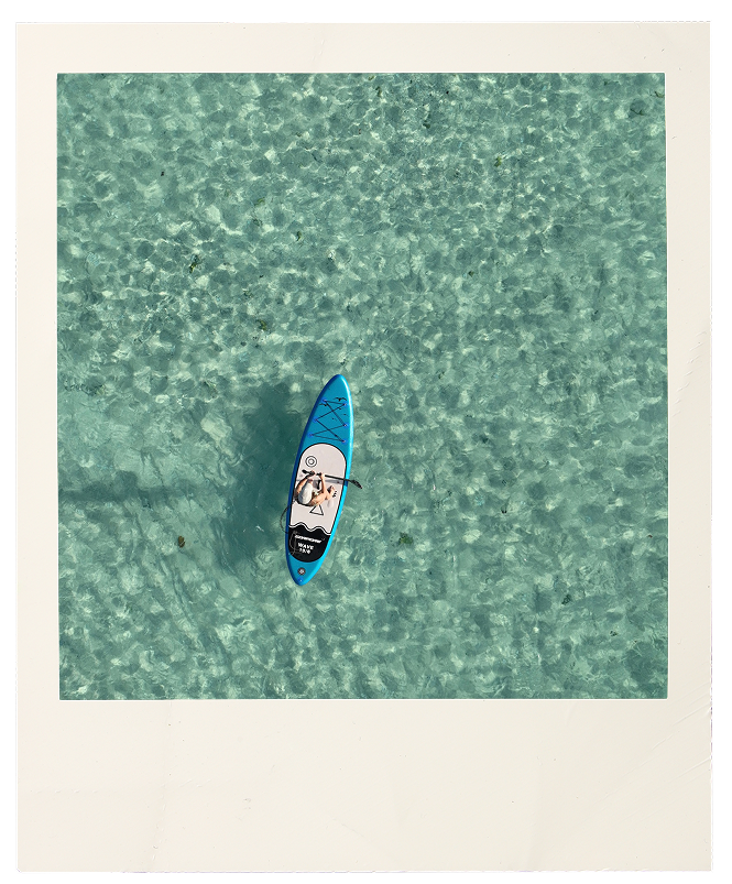Aerial view of a person on a paddleboard in crystal clear turquoise water
