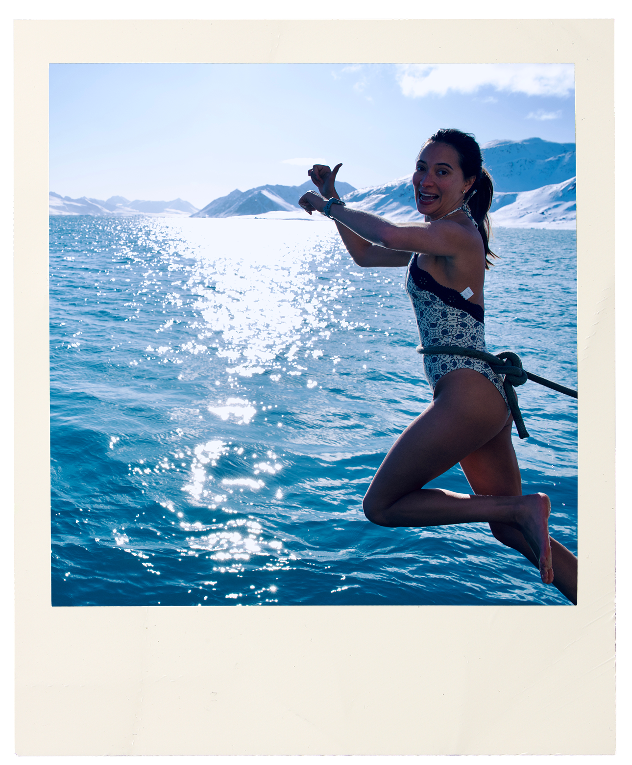 Gia Schiffino, Travel Designer at Lux Voyage, jumping from a boat rope over sparkling polar waters