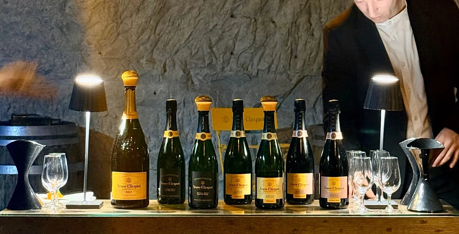 Row of Veuve Clicquot champagne bottles lined up for a private tasting in a stone wine cellar