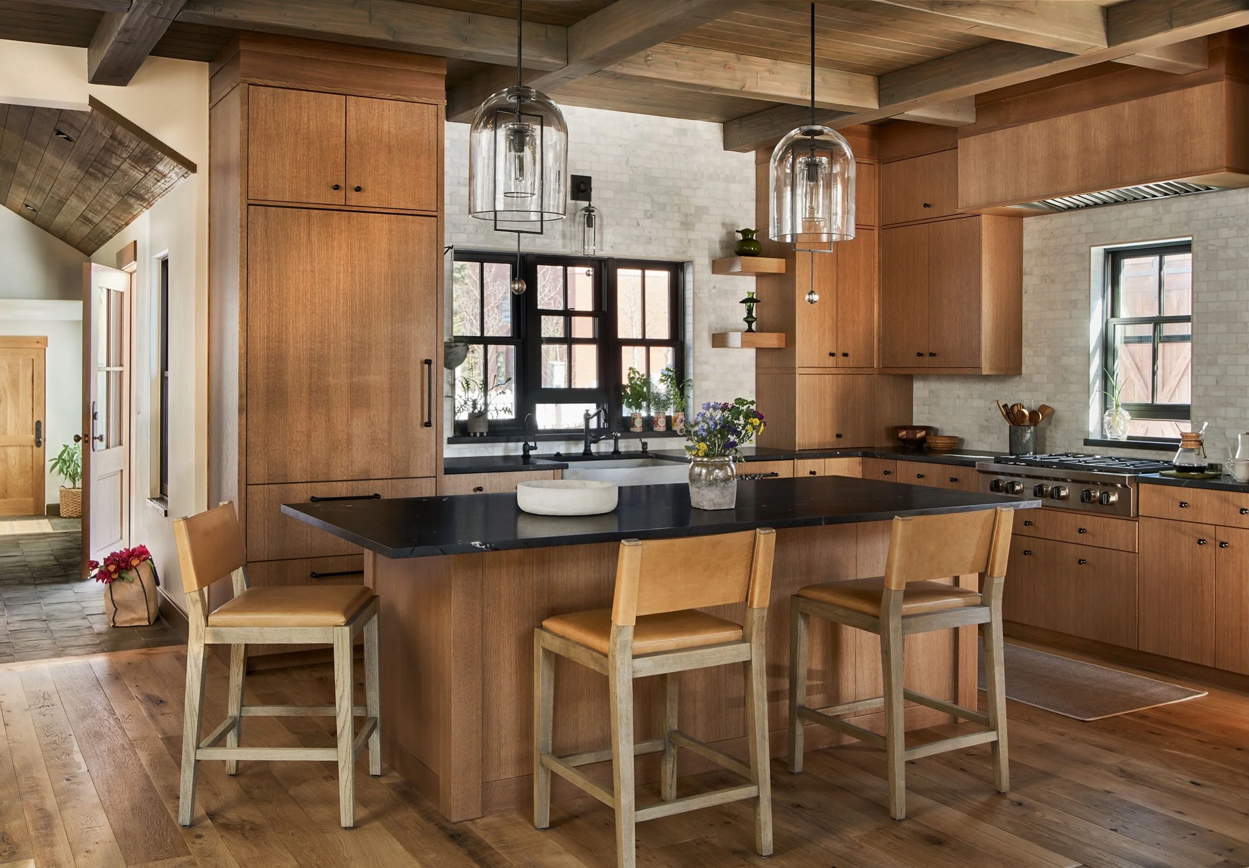 The heart of the home will always be the kitchen, a place to gather and enjoy food and company.  In these historic remodels it&rsquo;s often labeled the connector where the existing meets the new.  We layered natural stone with warm wood tones in a c