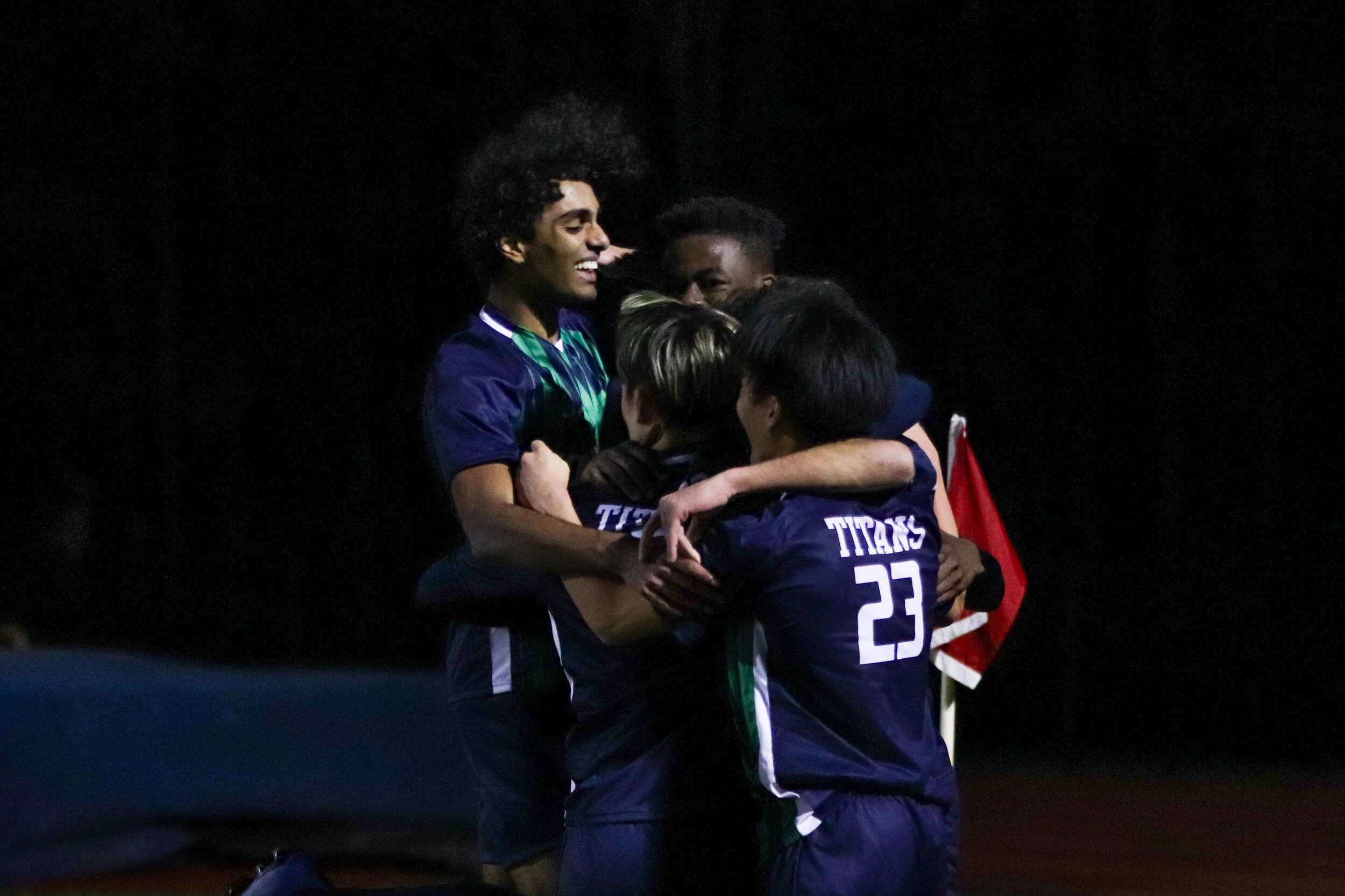 Boys Varsity Soccer fall into a group hug after winning a region game.