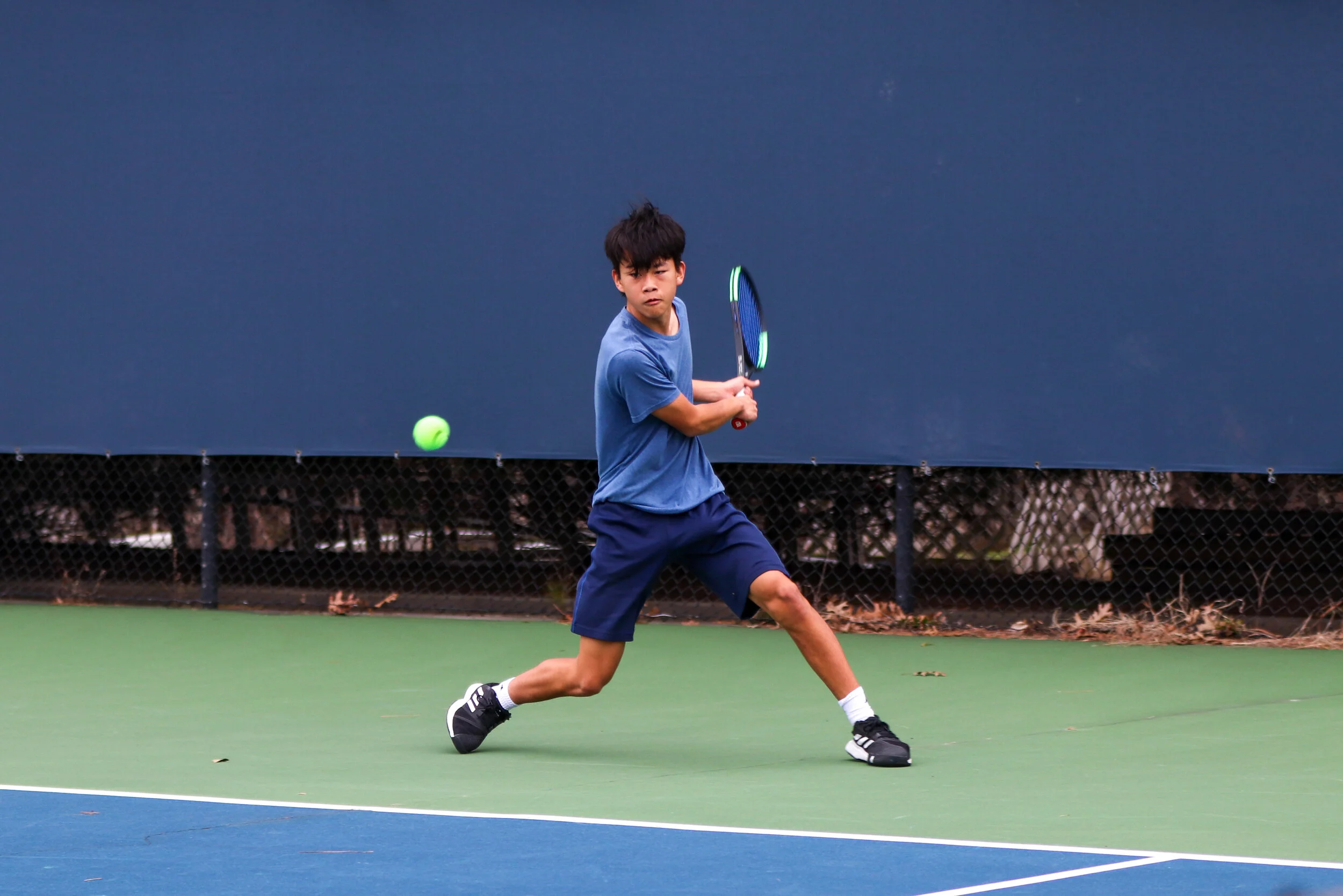 Freshman Jonathan Chen swings at the tennis ball.