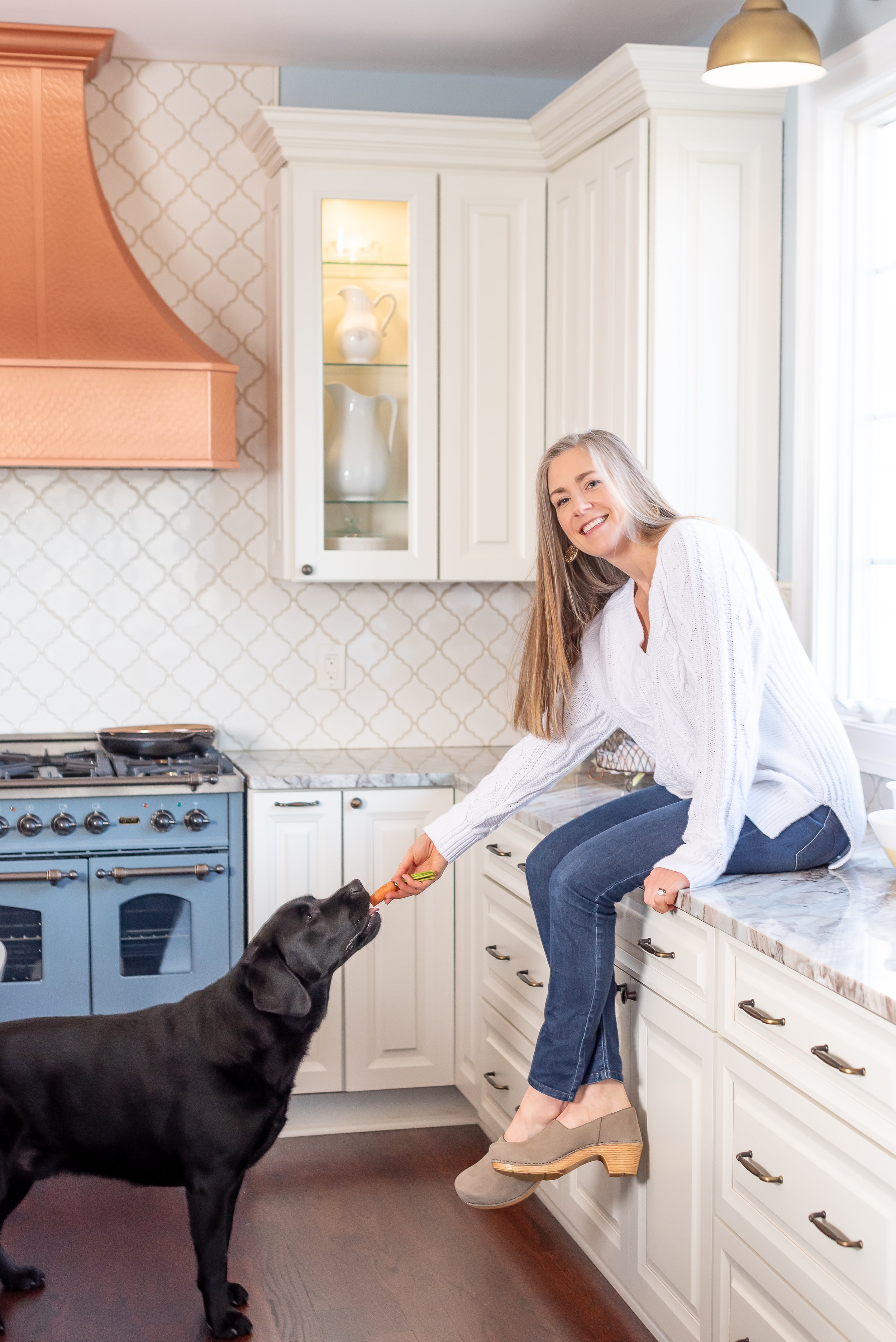 Dr. Meghan Hulver with her black lab in her kitchen