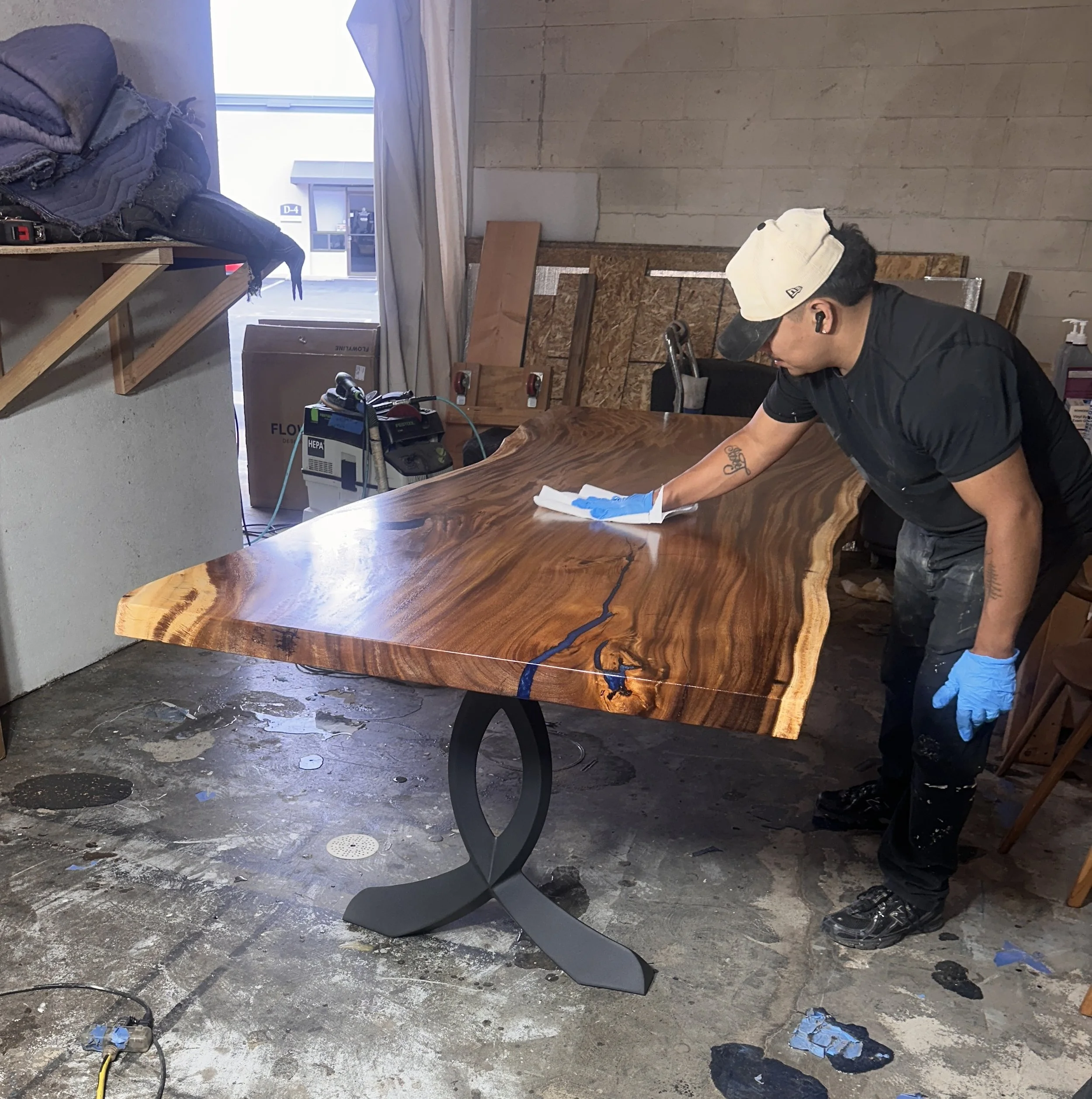 Craftsman hand finishing a custom live edge wood table at the Indigenous by La Rue workshop in San Marcos, CA