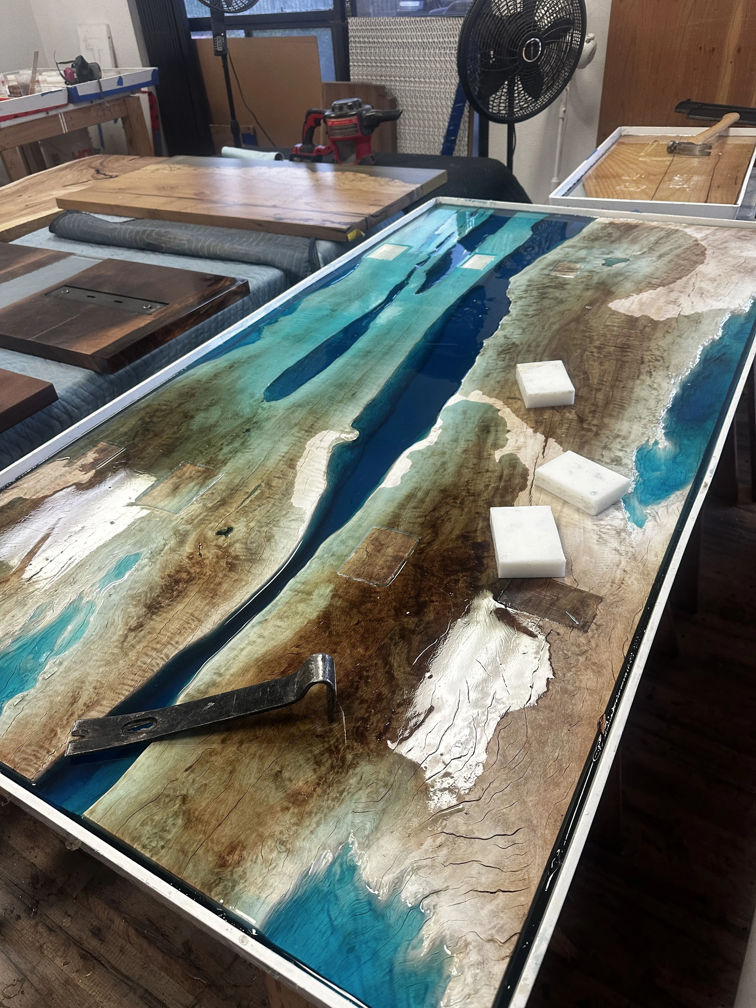 Blue epoxy resin river table curing in a temperature- controlled workshop at Indigenous by La Rue
