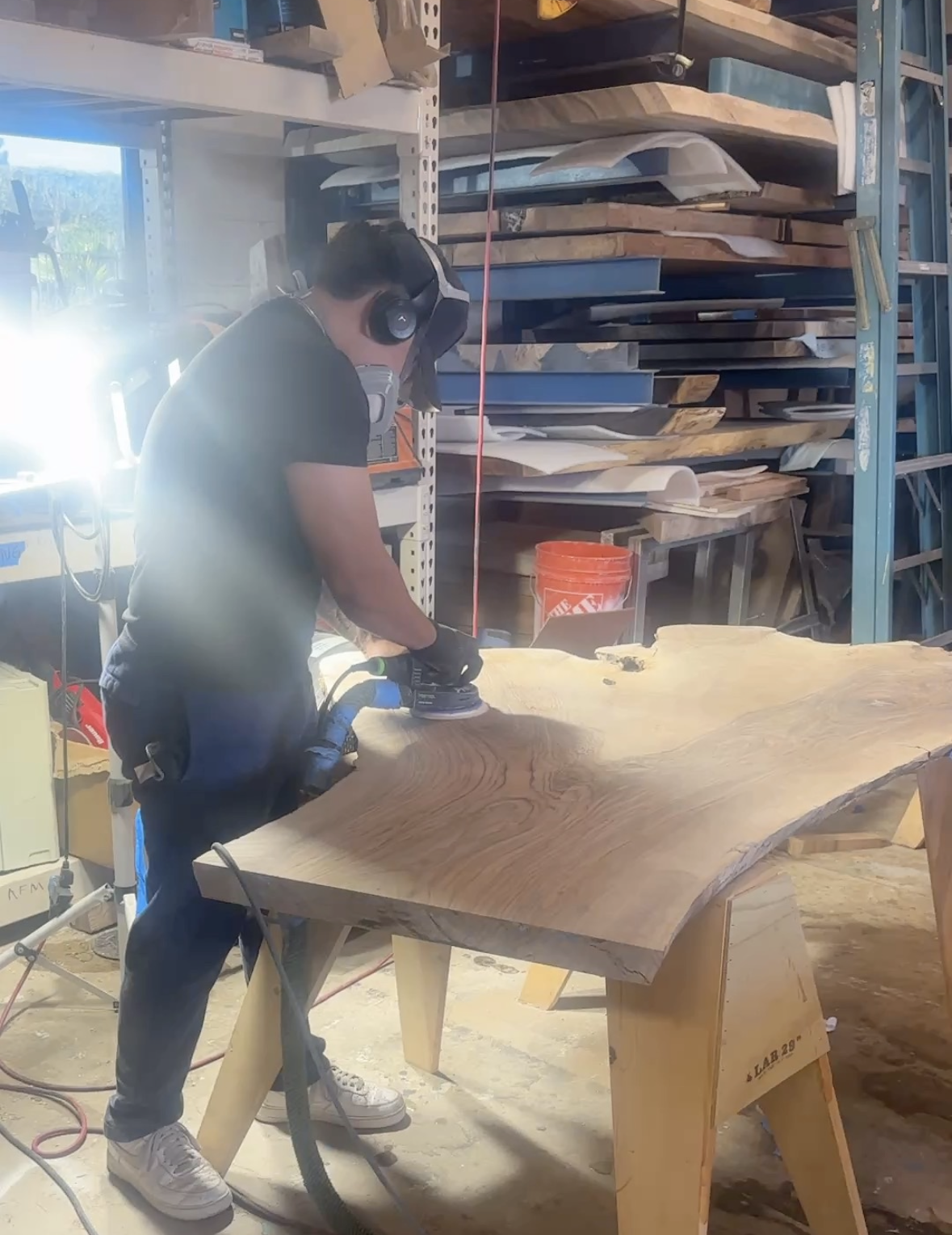 Craftsman sanding a custom live edge wood table at the Indigenous by la rue workshop in san marcos ca.