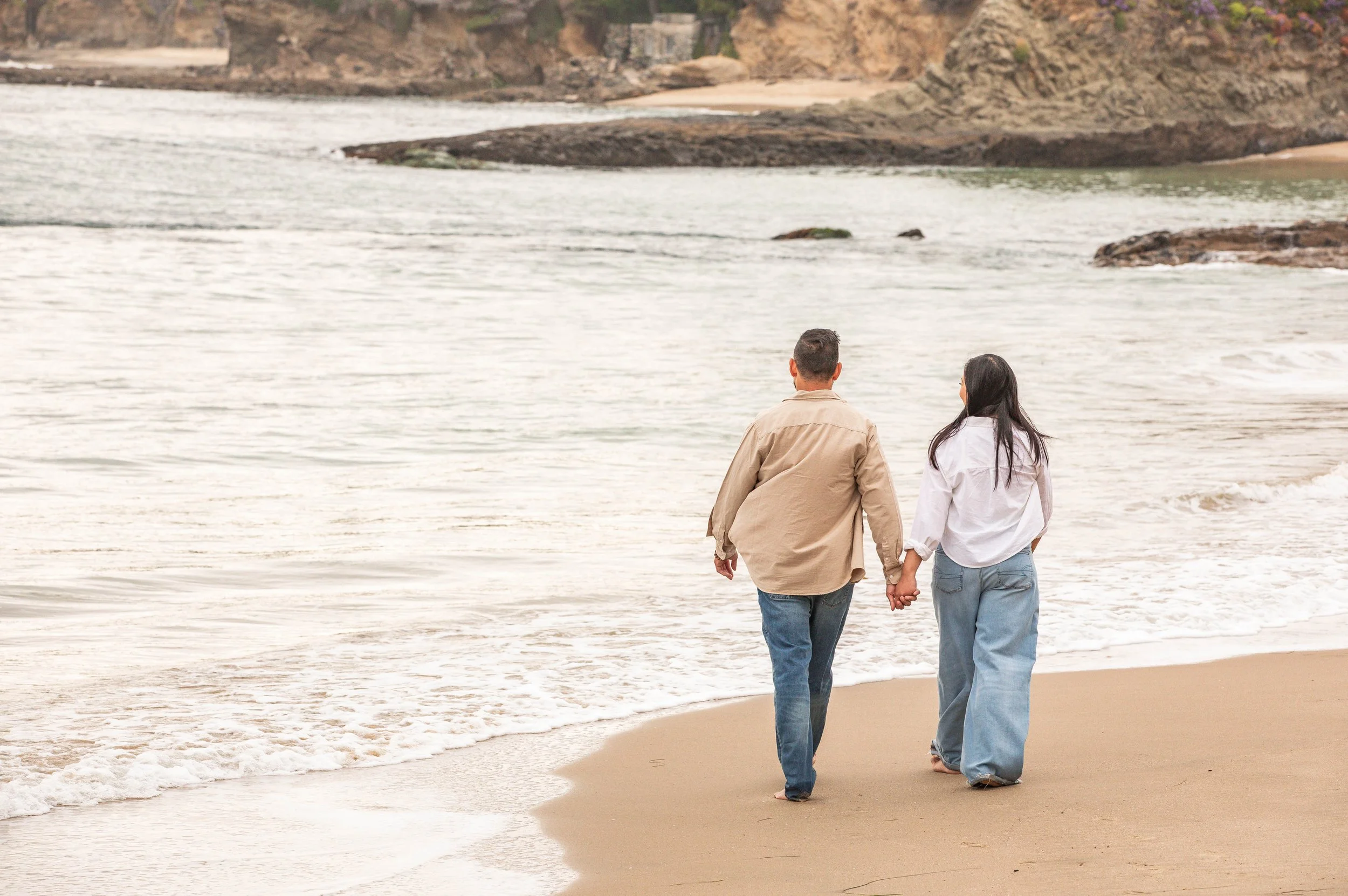 Couple walks hand in hand along the beach Laguna Beach California