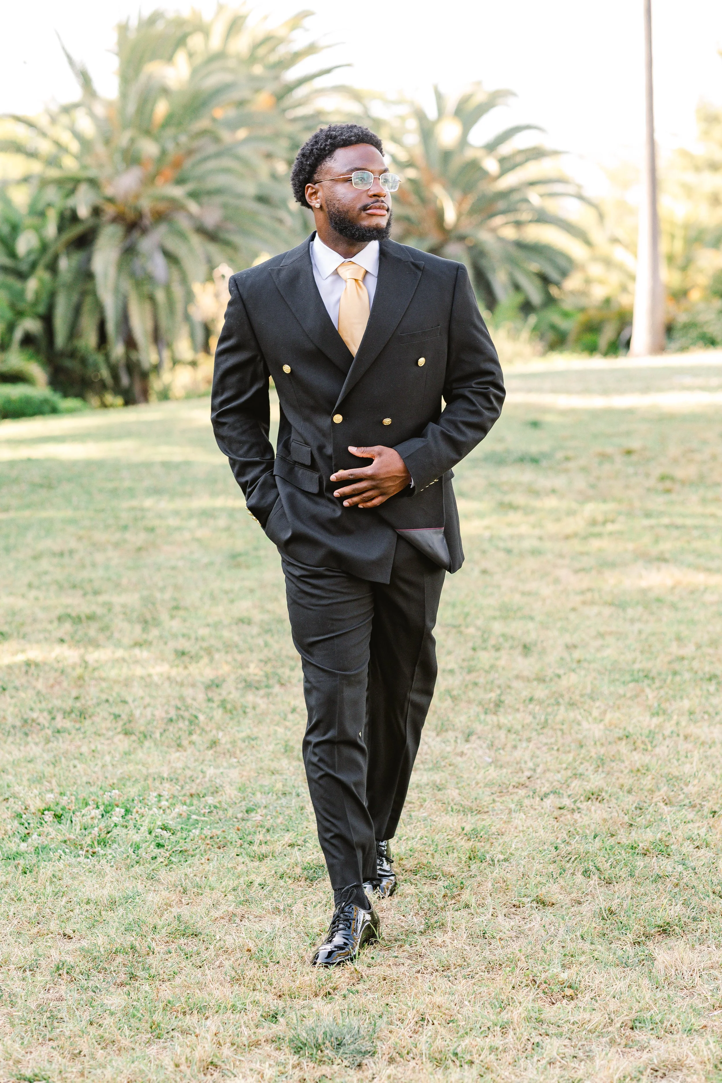College graduate walks along the grass during portrait session at Avril Park in San Pedro, California.jpg